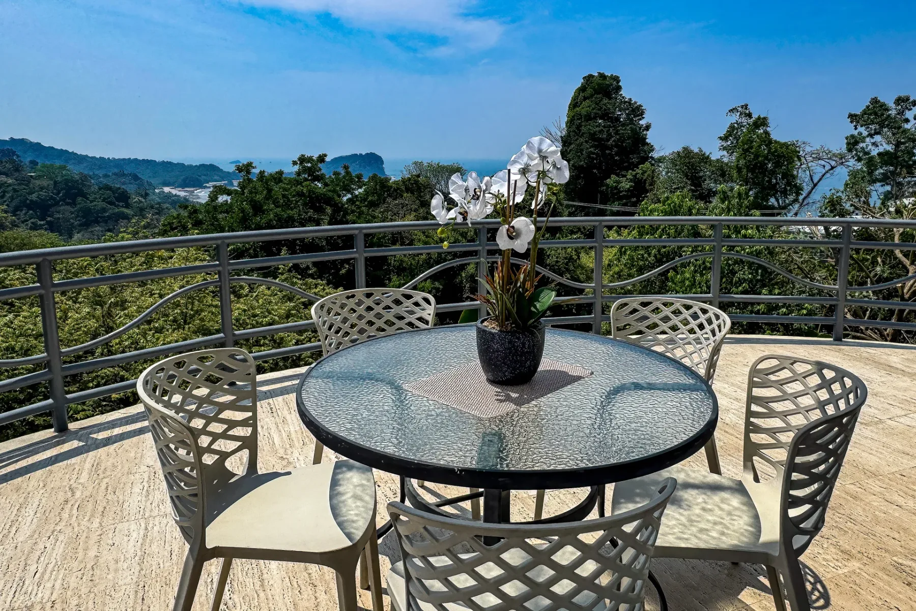 An outdoor patio dining area overlooks a green, wooded landscape.