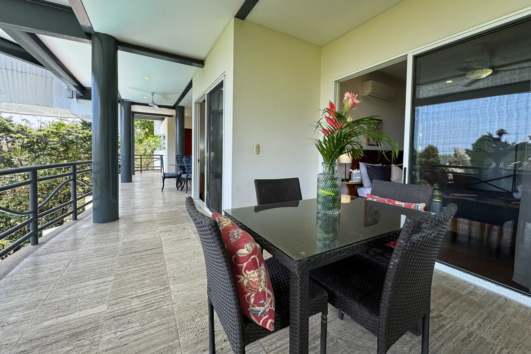 A covered outdoor dining area with a table and dark woven seating.