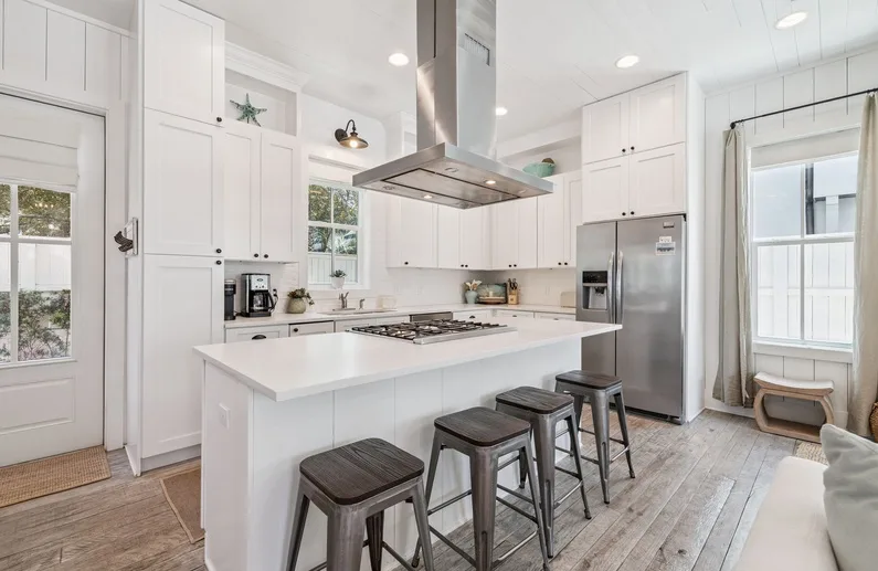 A bright kitchen with white cabinets, a central island, and stainless steel appliances.