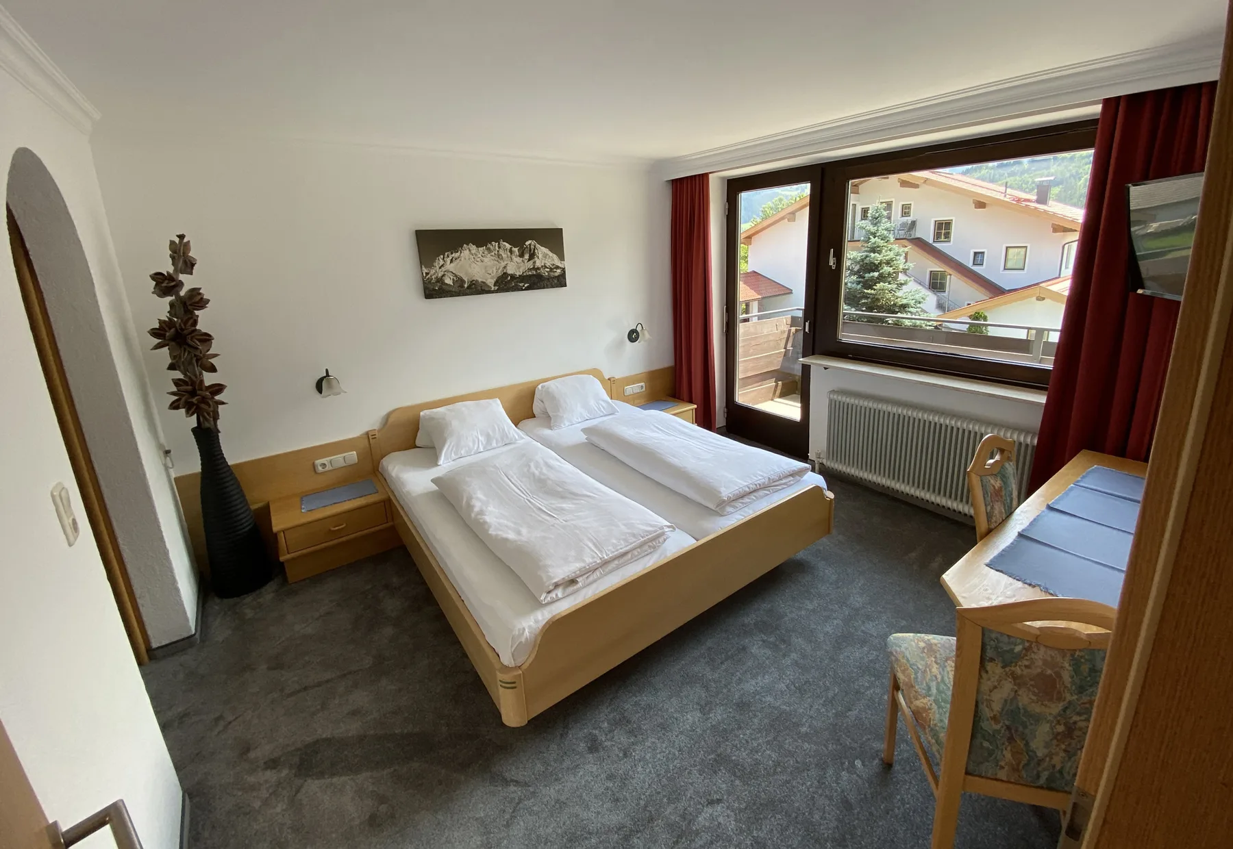Un dormitorio con dos camas, un escritorio y una ventana grande.