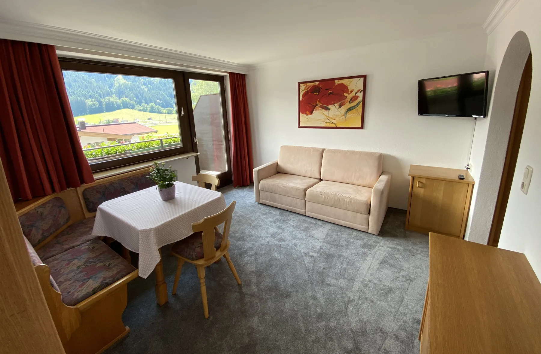 Una sala de estar con asientos alrededor de una mesa y un televisor en la pared.