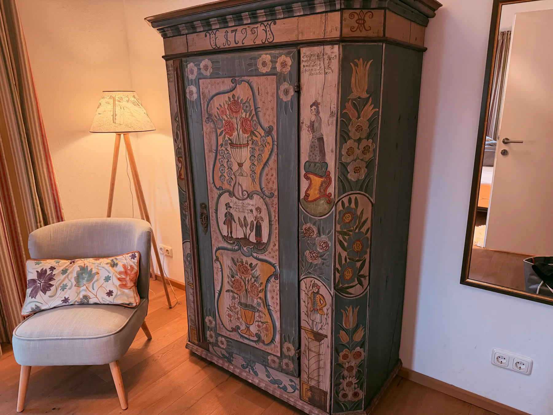 A warmly lit room with a painted wooden cabinet and upholstered seating.