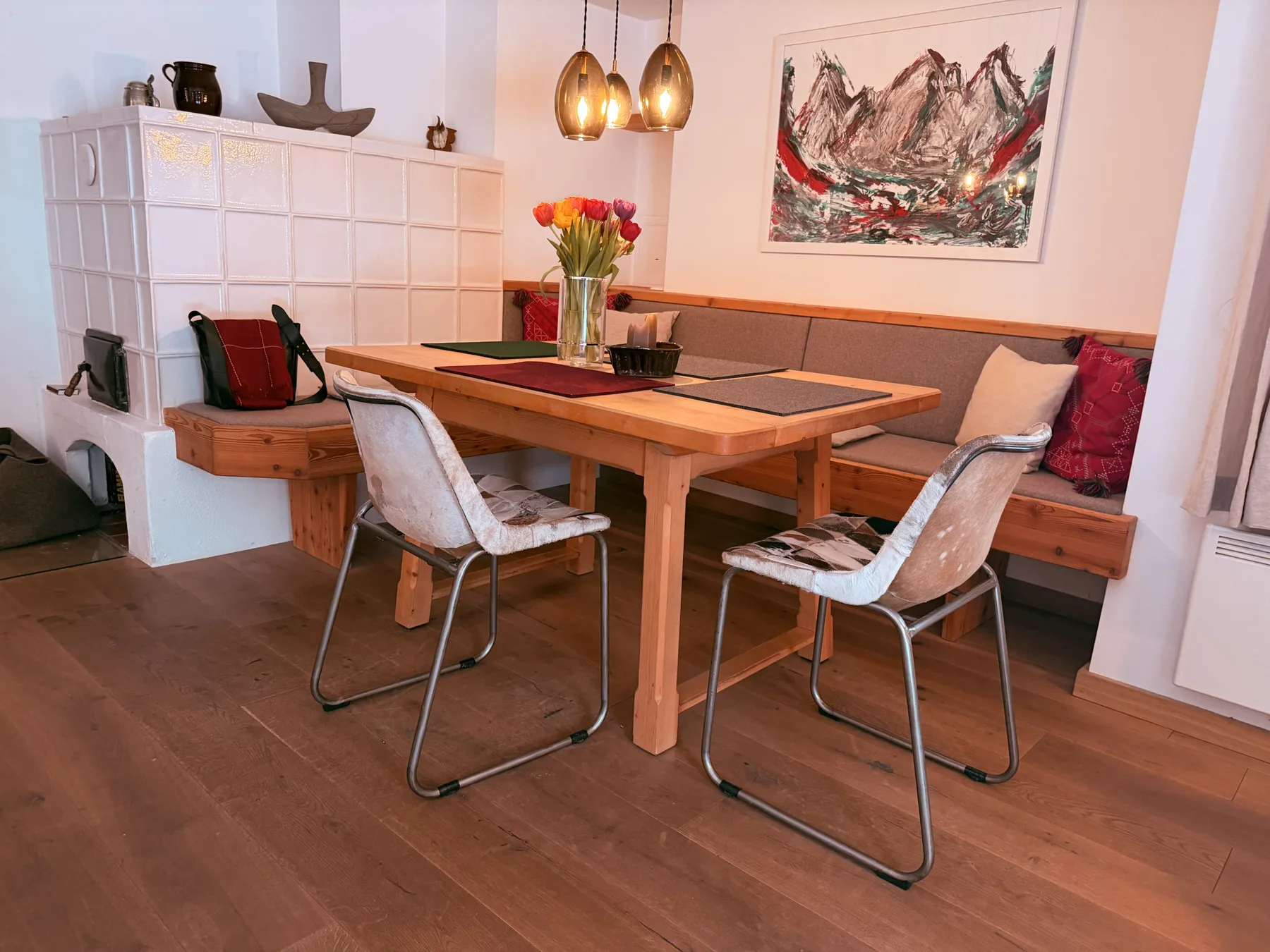 A dining area with a wooden table, seating, and mountain artwork on the wall.