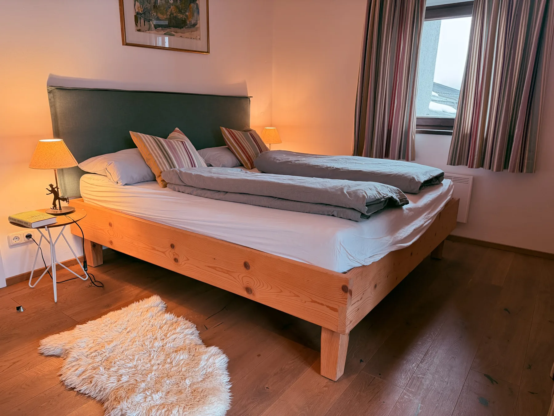 A bedroom with a large bed, bedside lamps, and a window.