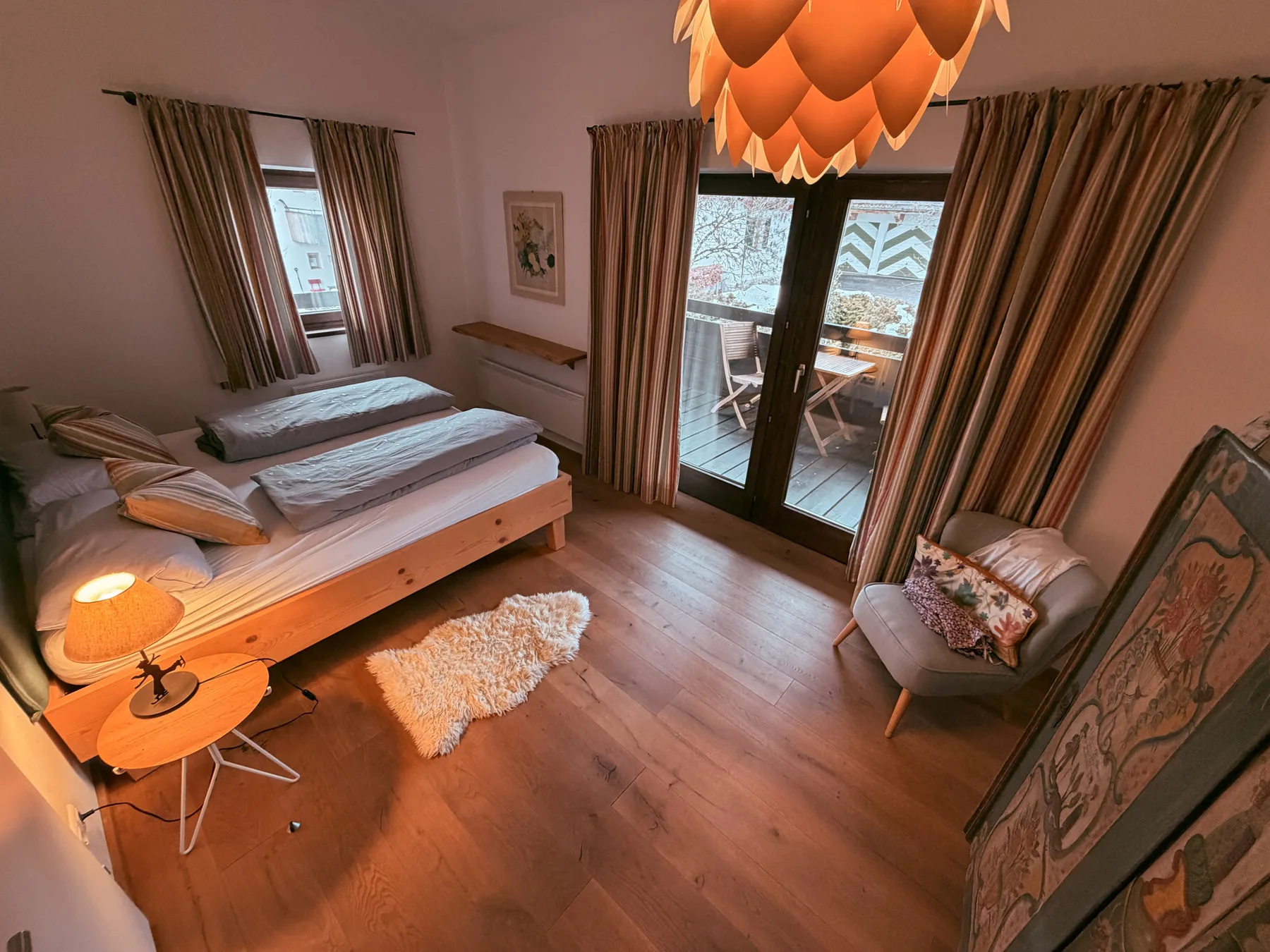 A bedroom with a bed, a chair, and glass doors opening to a balcony.