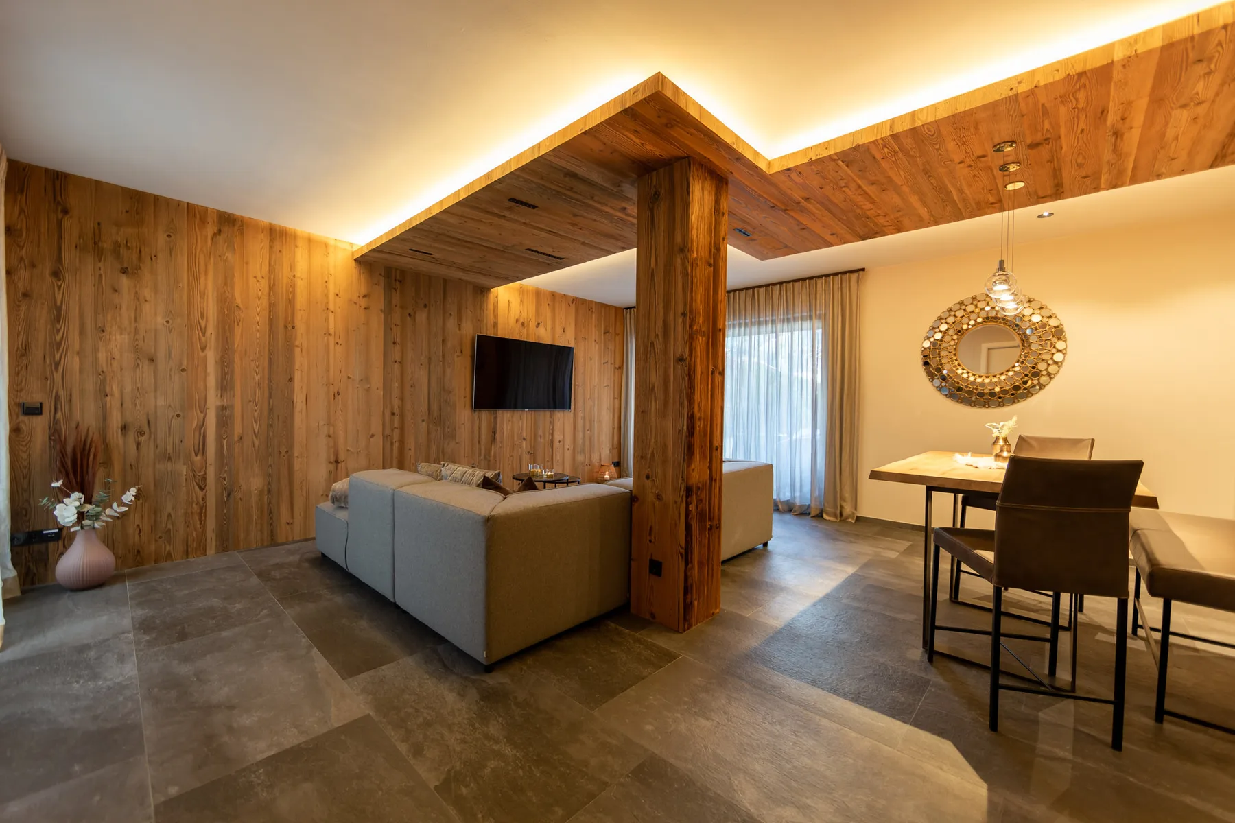 A living and dining area with wood-paneled walls, seating, and a table.