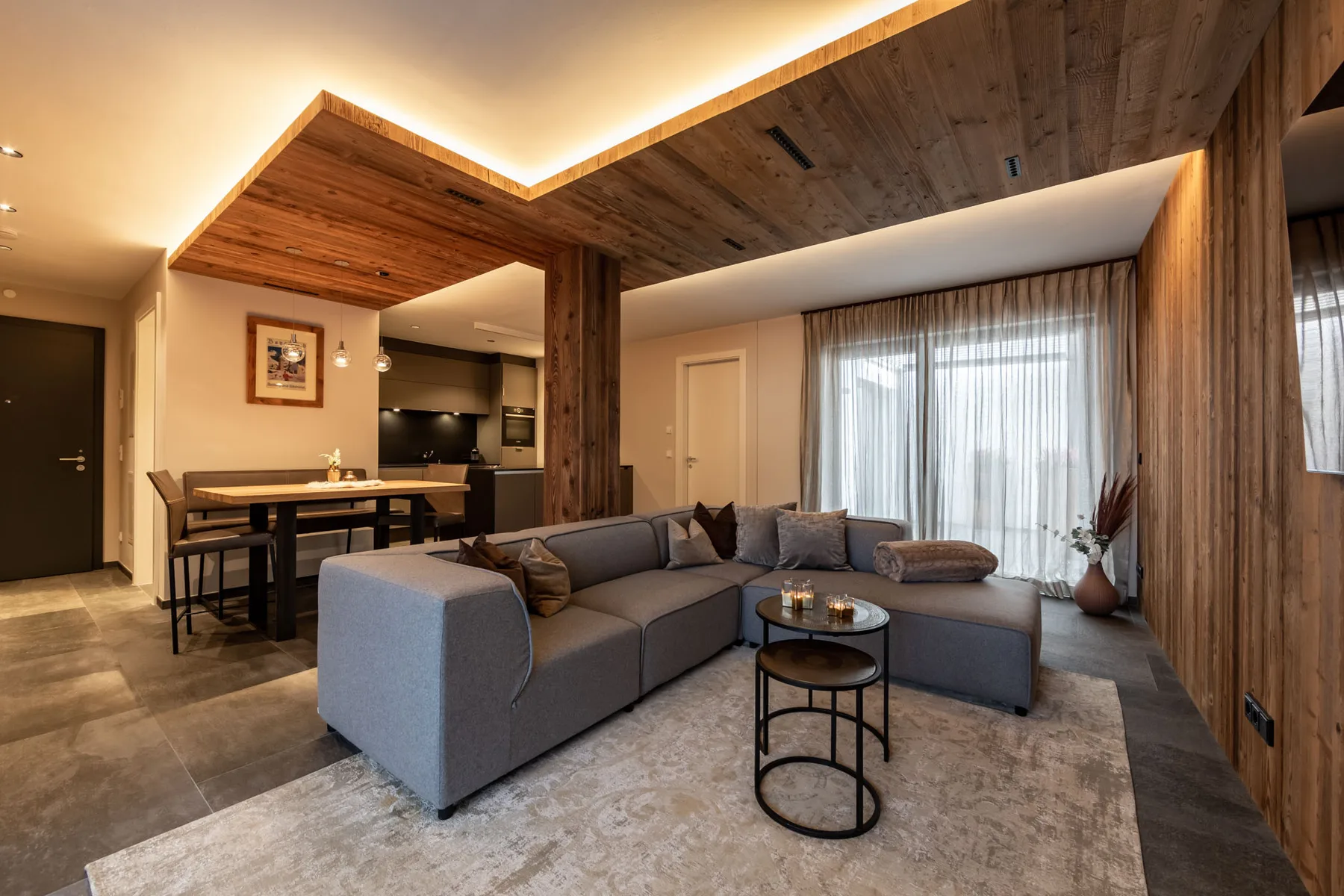 A modern living room with a sectional seating area beside a dining table.