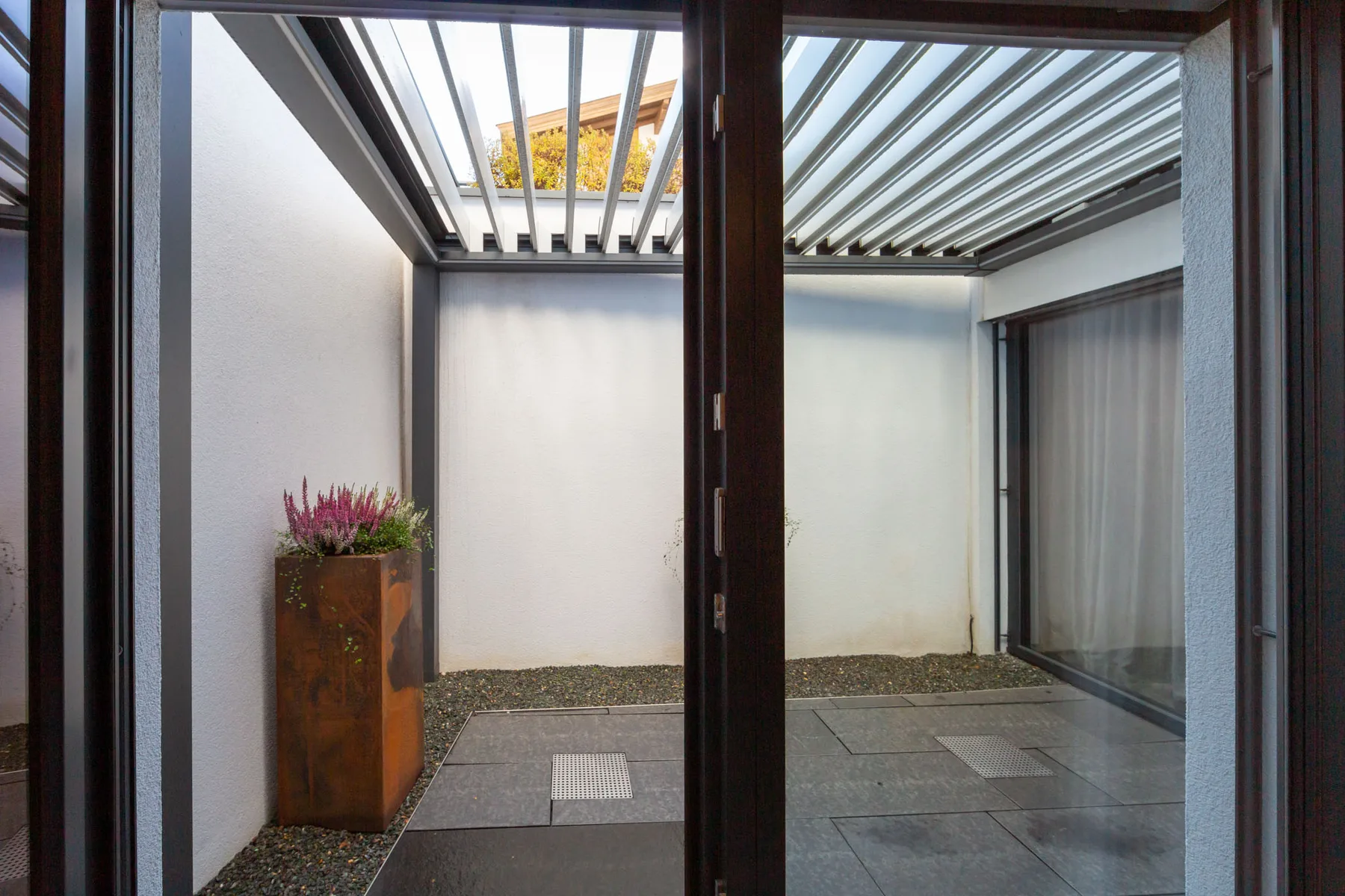 A small enclosed patio with gray paving and a planter.