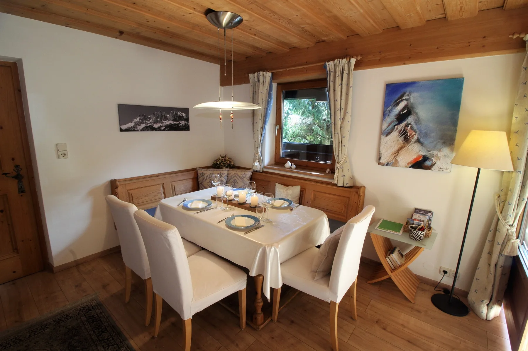 A dining area with a table set beneath a wooden ceiling.