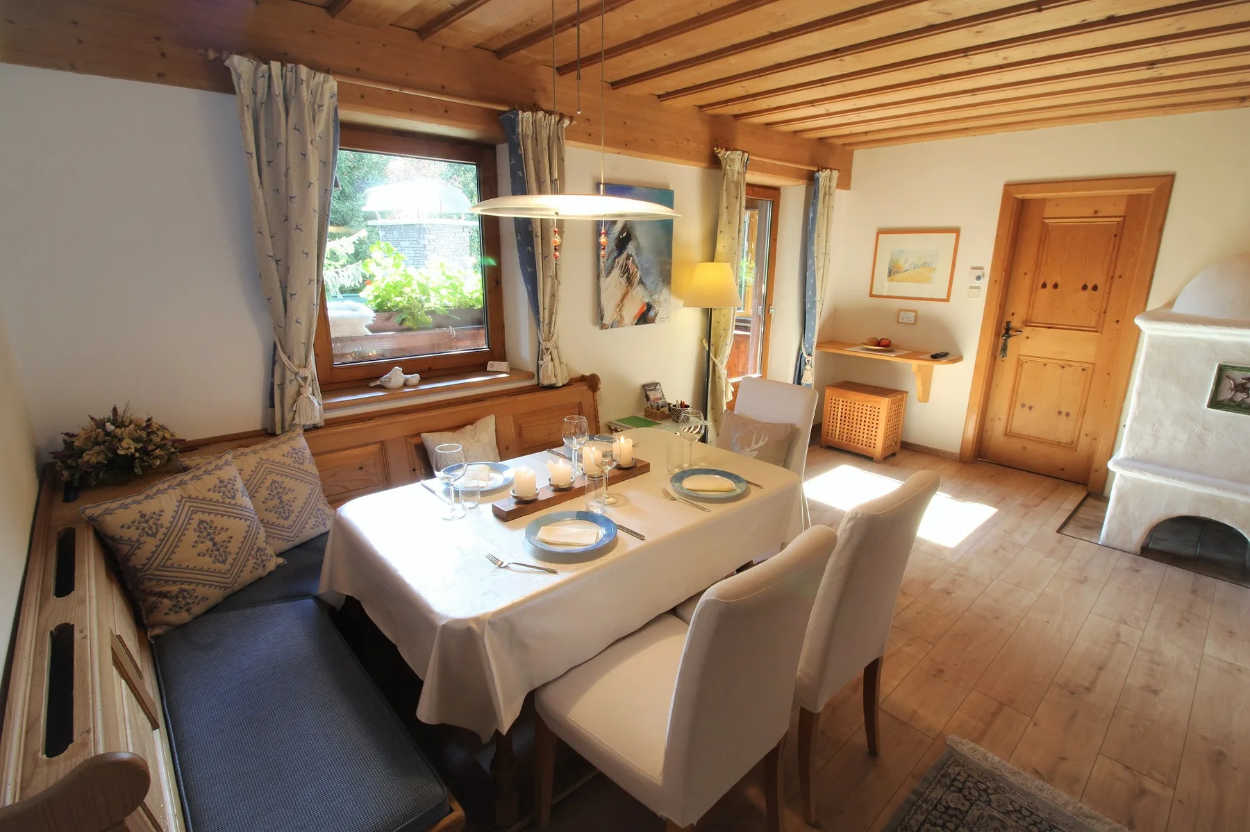 A dining area with a table set beside wooden windows and a built-in bench.