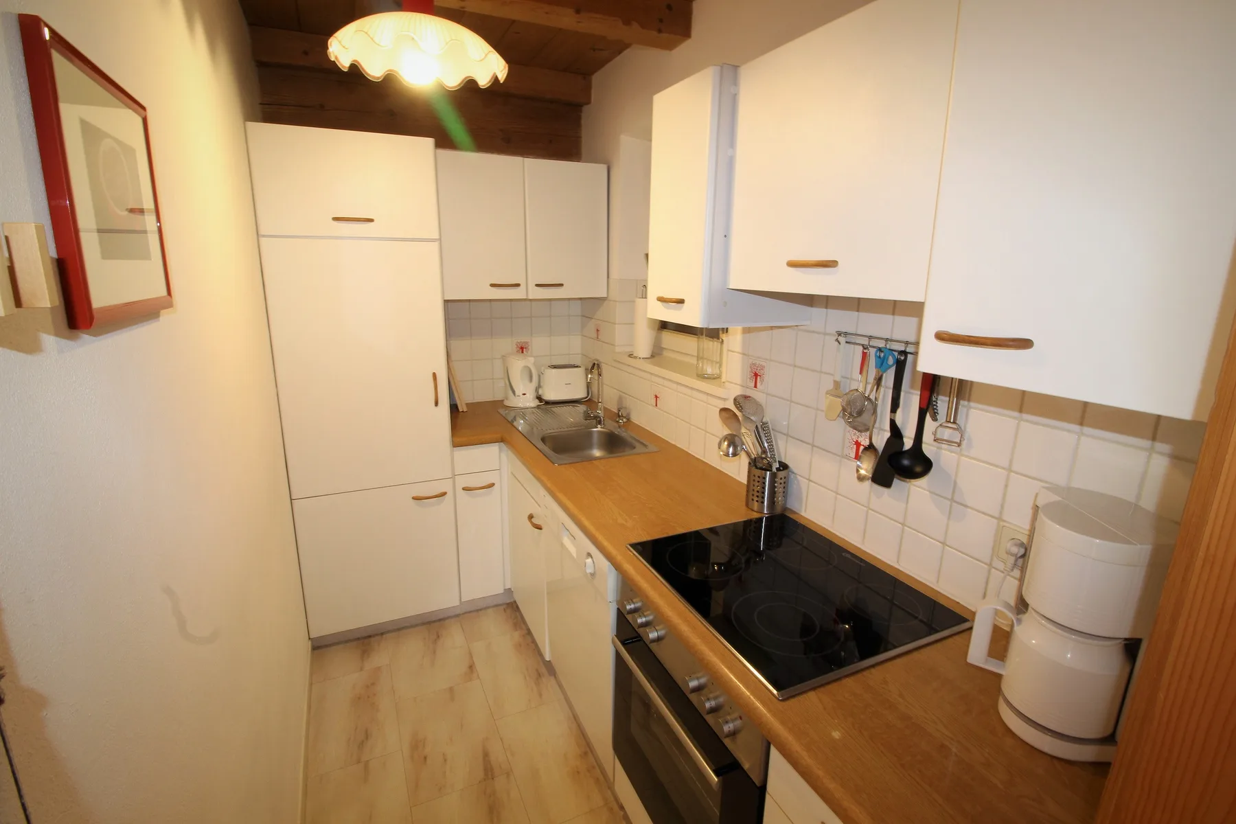 A compact kitchen with white cabinets, a wooden countertop, and a cooktop.