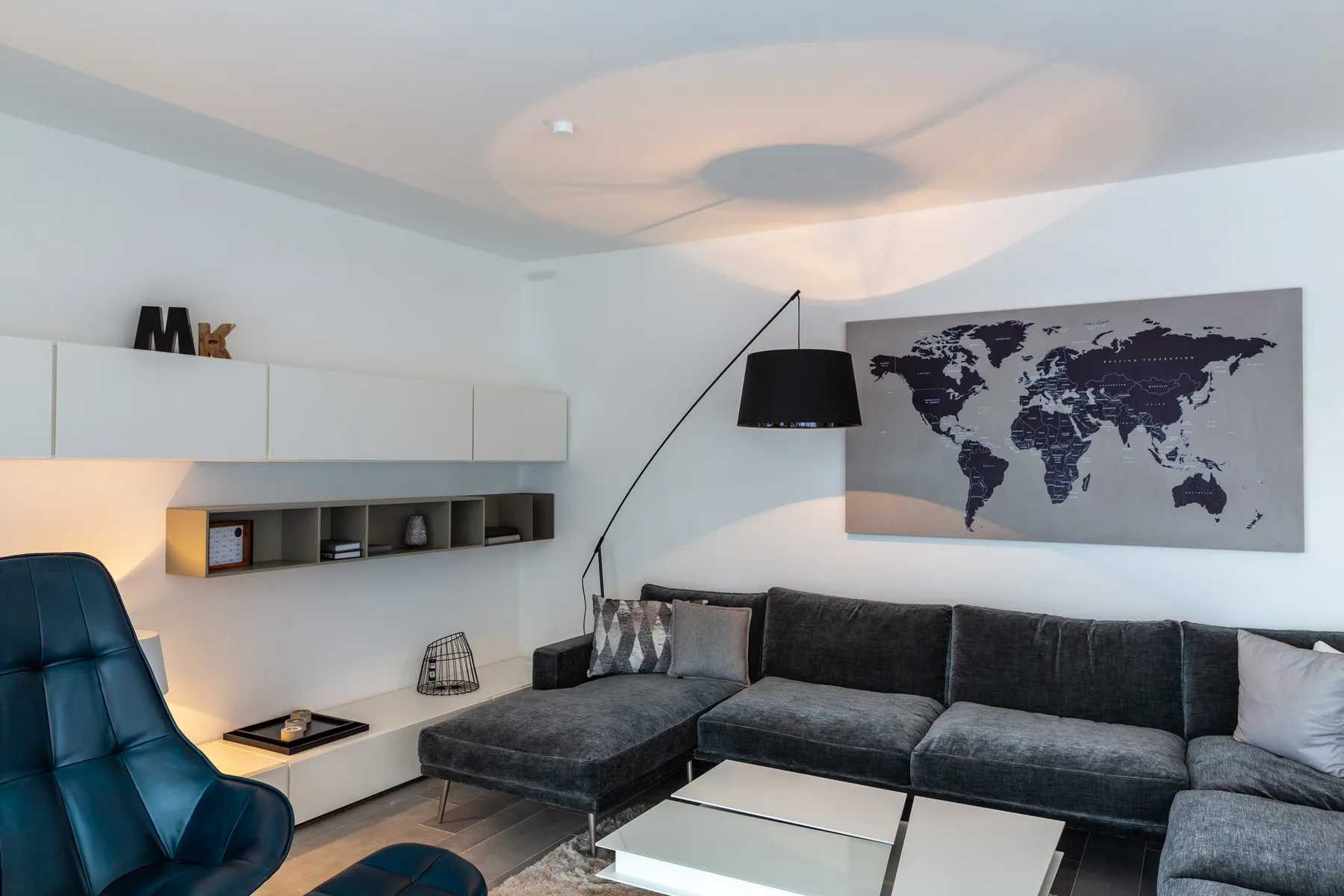 A living room with dark seating, a low table, and a world map wall print.