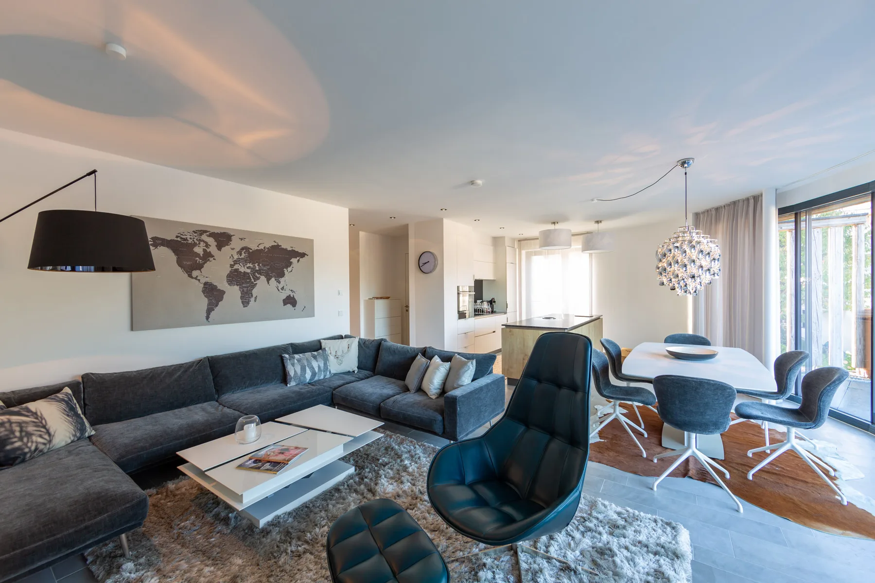 An open-plan living and dining area with seating beside large windows.
