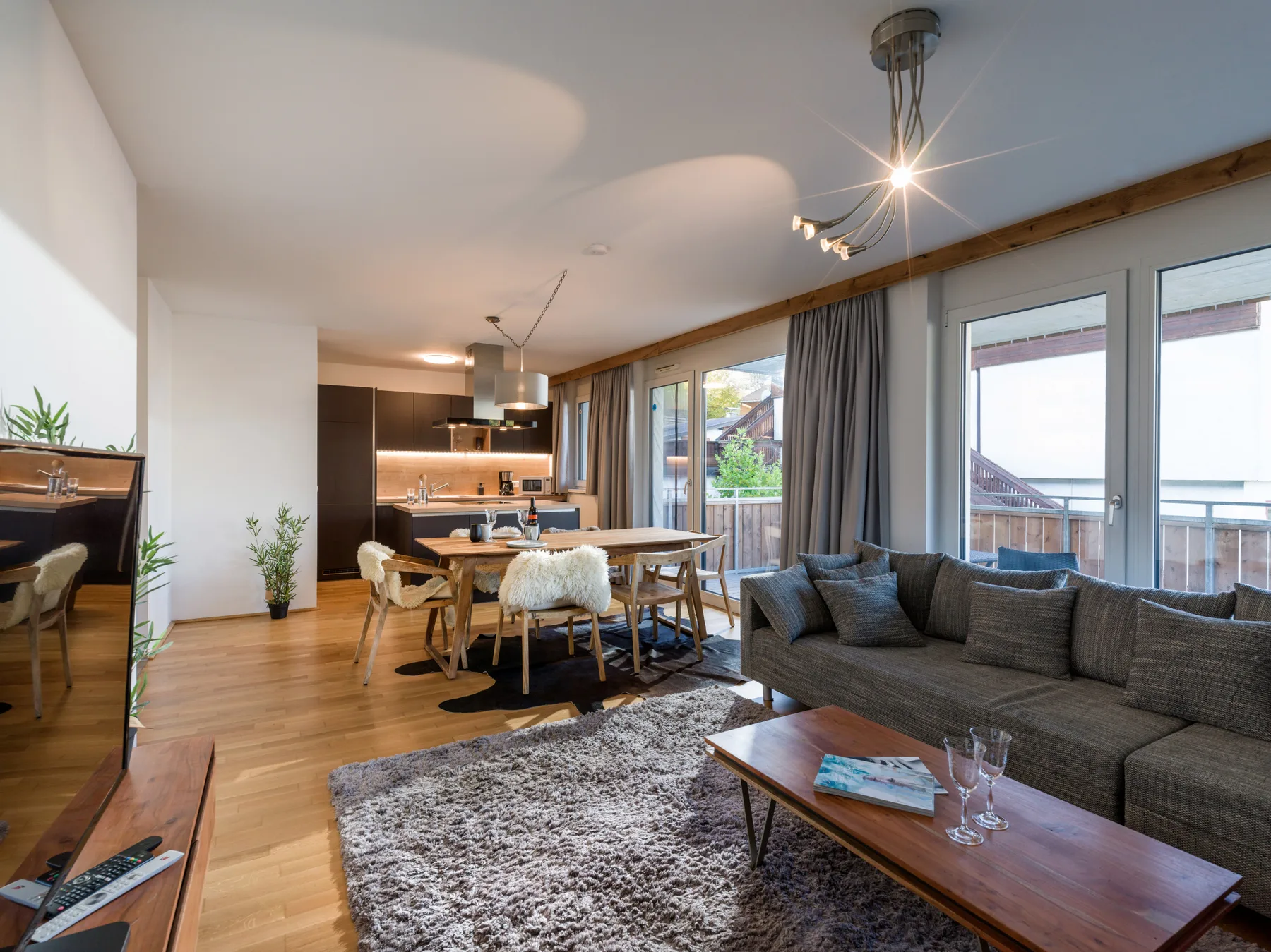 Sala de estar y comedor de planta abierta con cocina y ventanales.