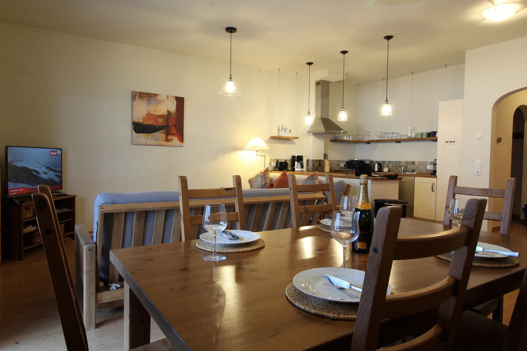 A dining area with a wooden table and open kitchen.