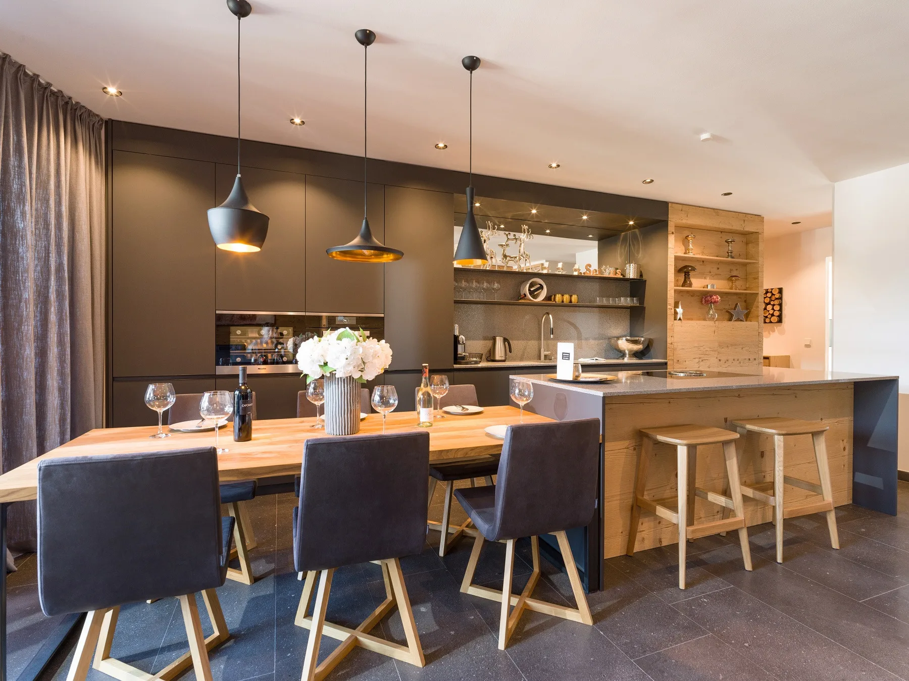 Una cocina y comedor modernos con una larga mesa de madera e isla.