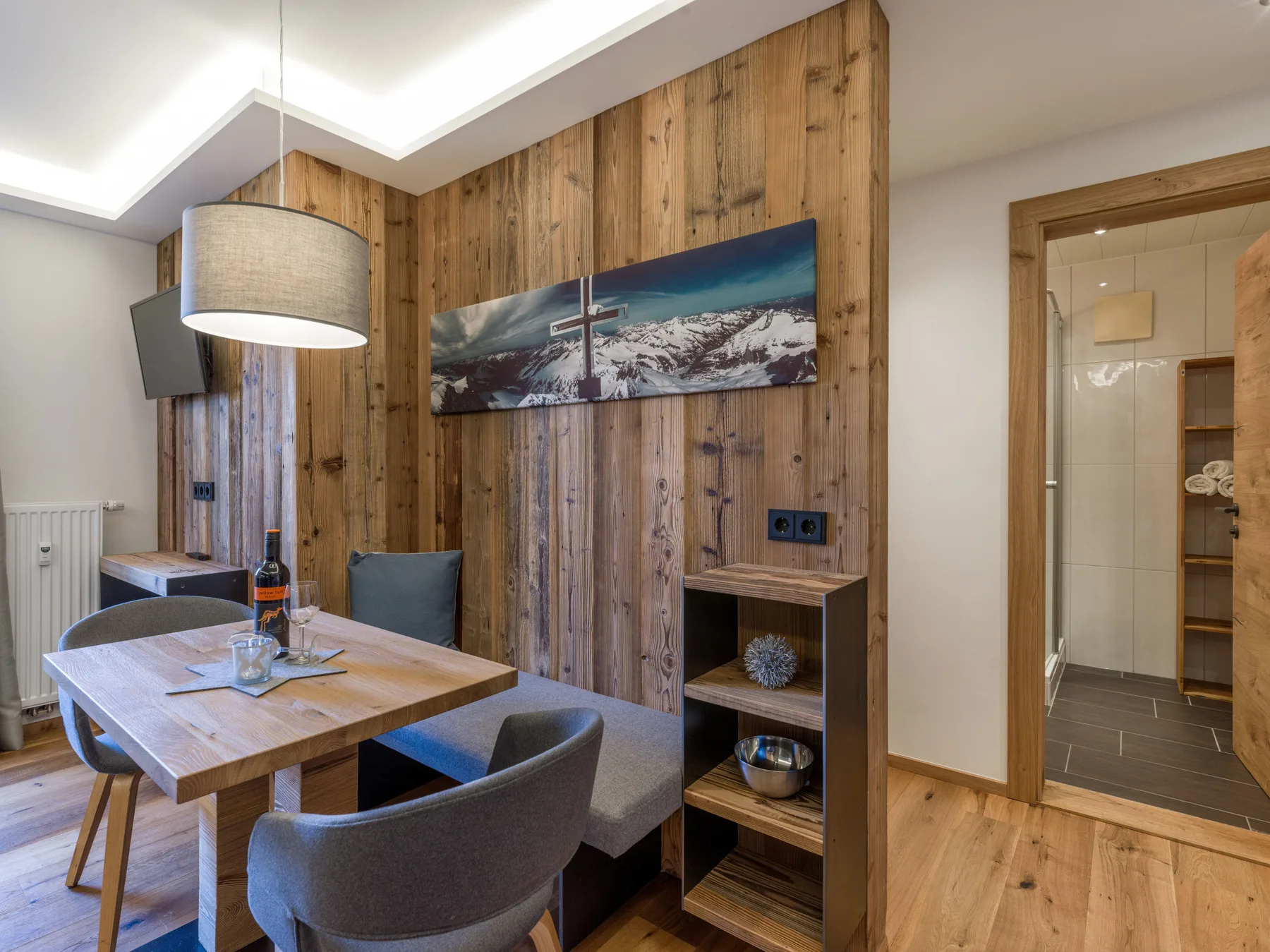 A dining area with a wooden table and chairs beside a wood-paneled wall.