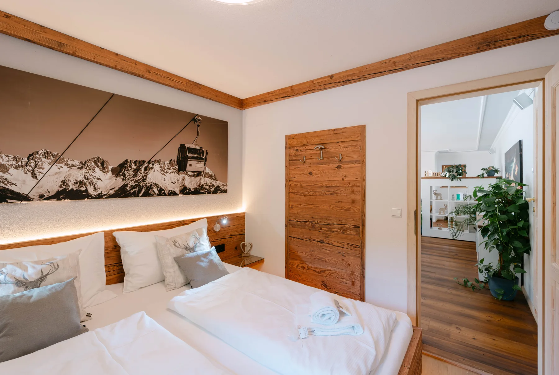 A bedroom with two beds, a wooden headboard, and a mountain photograph.