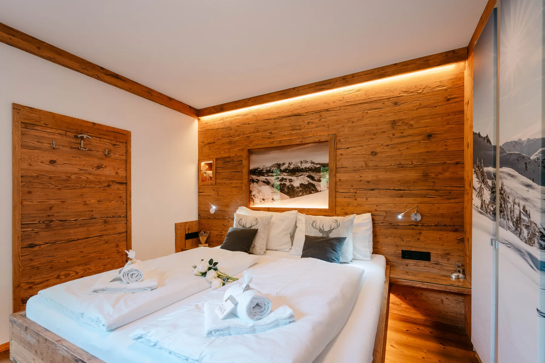 A bedroom with a neatly made bed and wood-paneled walls.