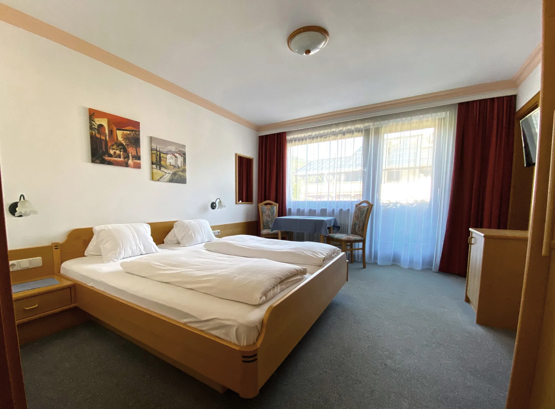 Un dormitorio con una cama doble y una mesa pequeña junto a la ventana.