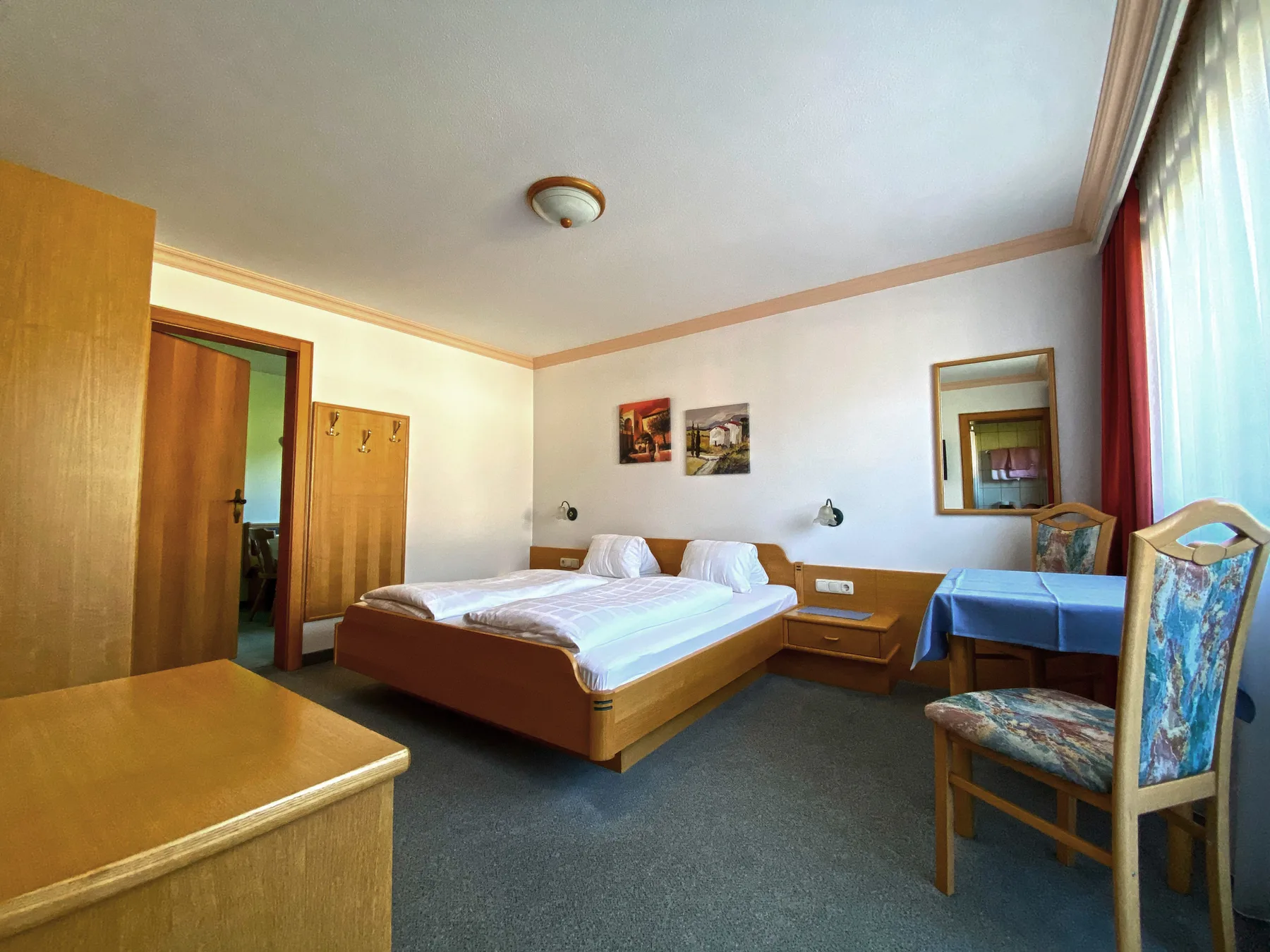 Dormitorio con cama doble, mesillas y un escritorio junto a la ventana.
