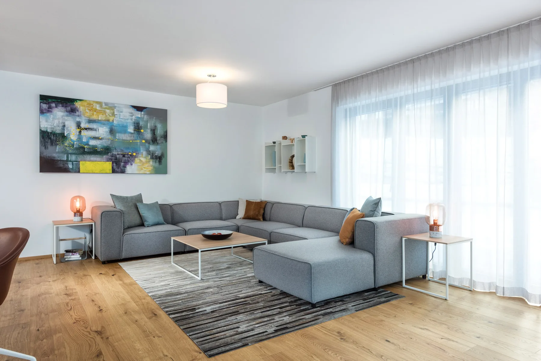 Living room with sectional seating, a coffee table, and large curtained windows.