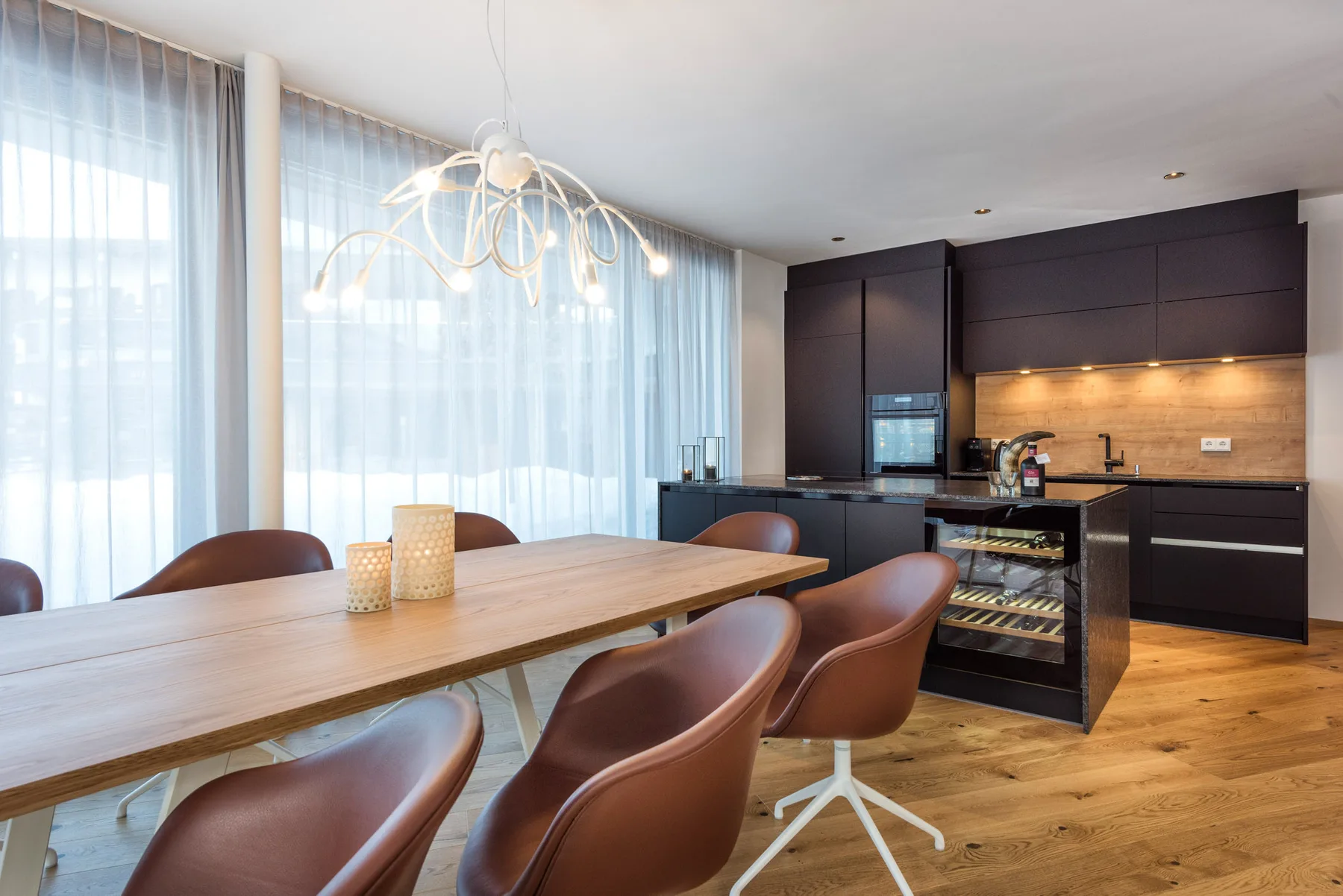 A dining area with a long table beside a modern kitchen.