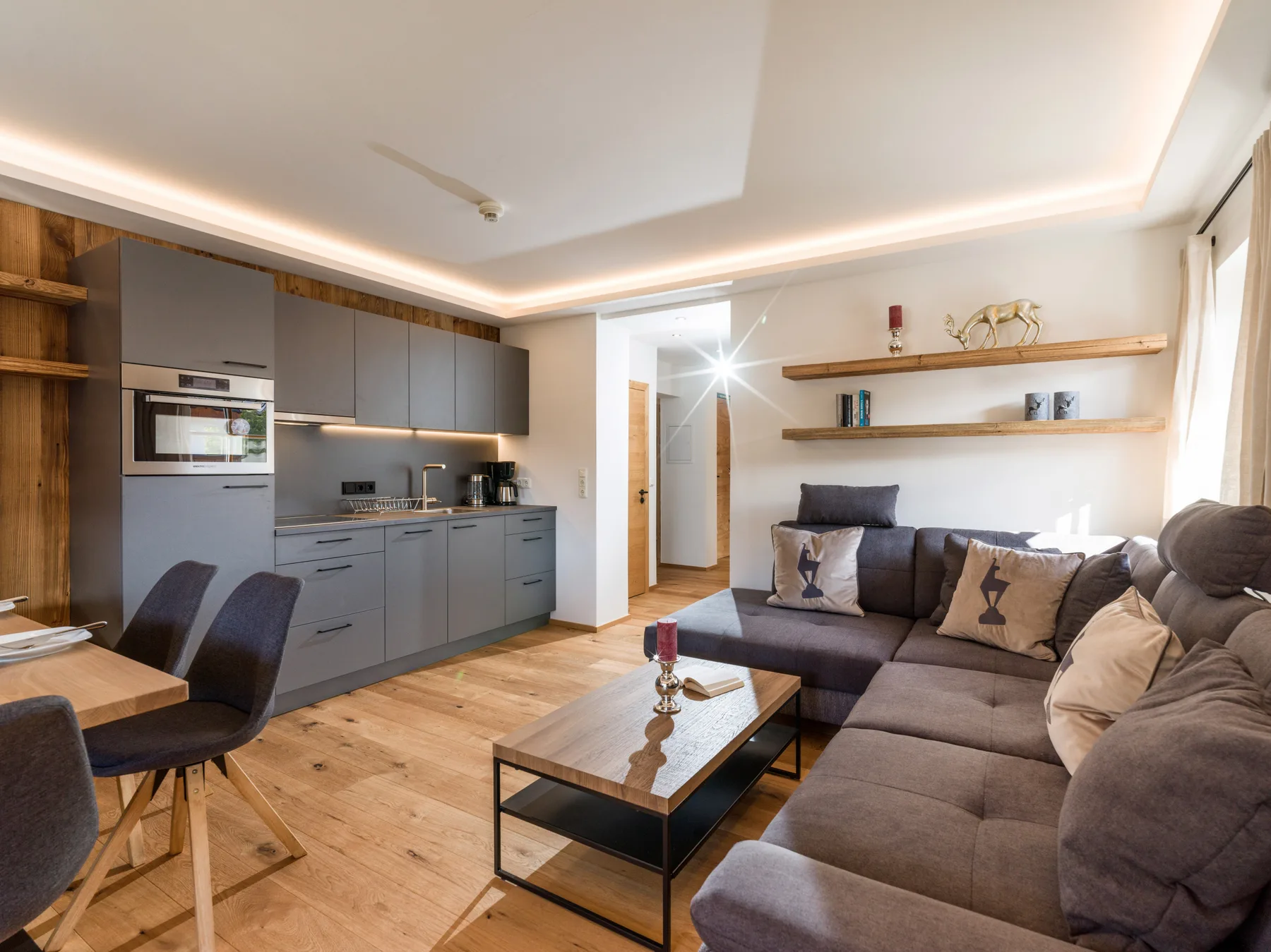 Una sala de estar moderna y abierta con cocina, mesa de comedor y asientos seccionales.