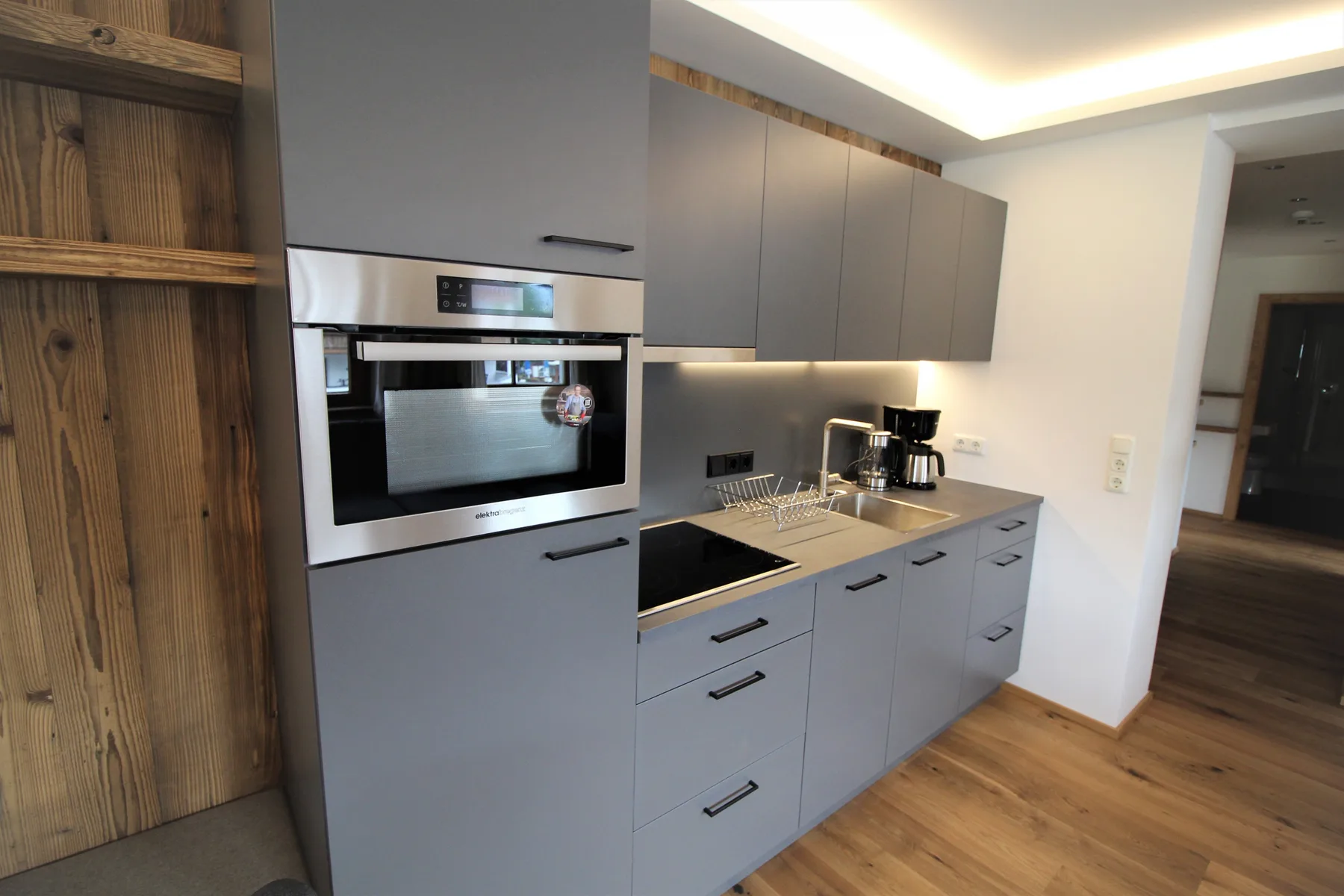 Una cocina moderna con gabinetes grises, electrodomésticos empotrados y una encimera.