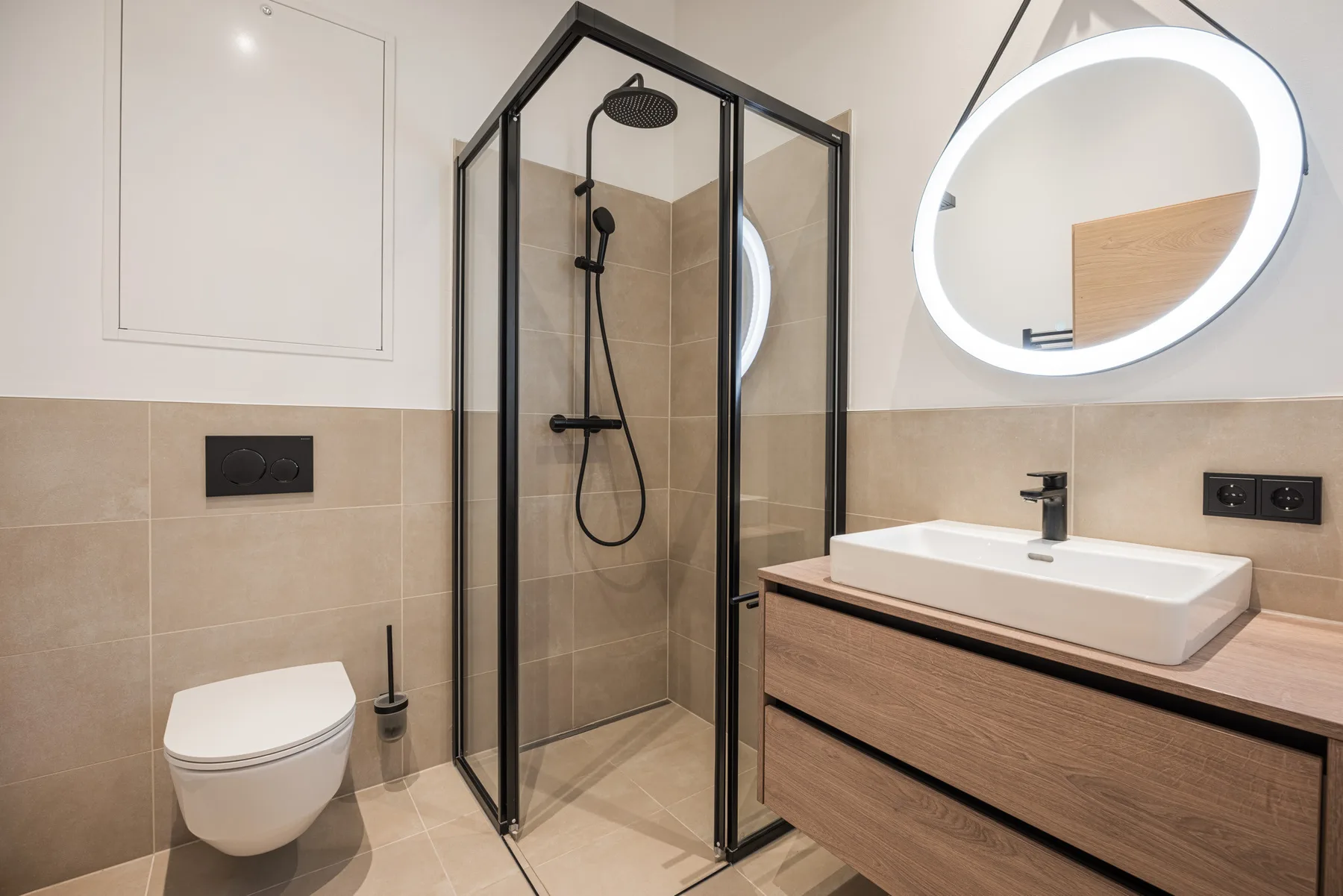 A modern bathroom with a glass shower, wall-mounted toilet, and vanity.
