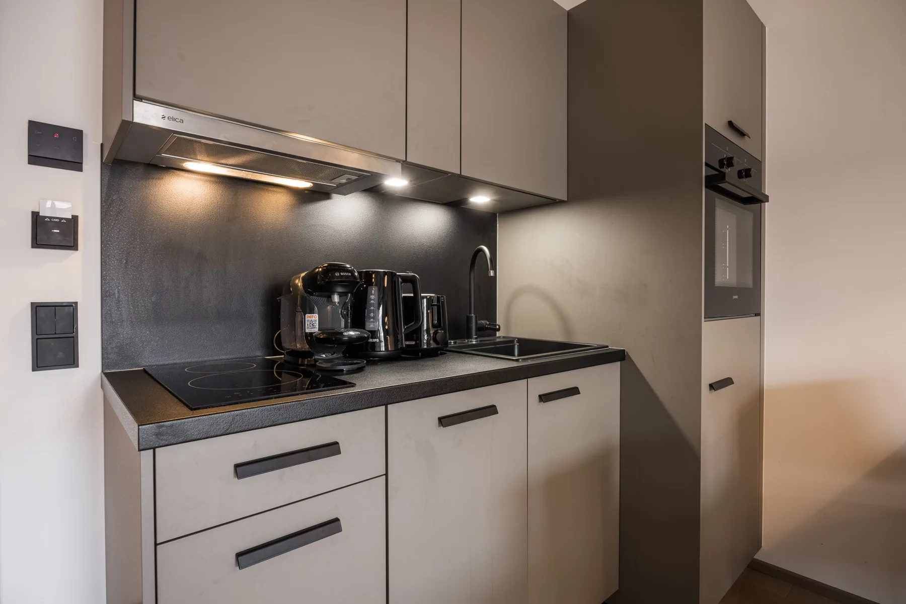 A modern kitchen with a cooktop, coffee machine, and built-in oven.