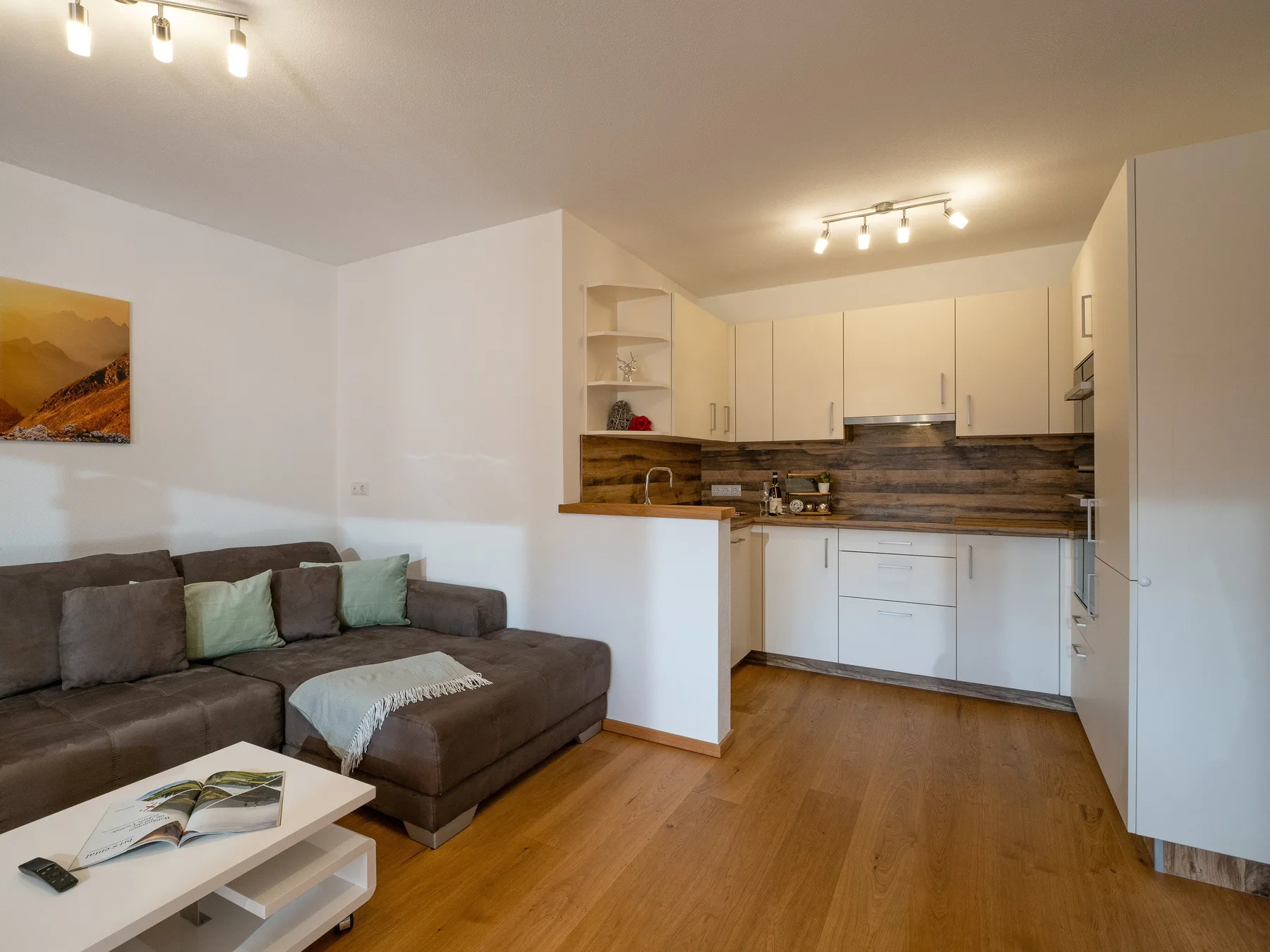 Una sala de estar se abre a una cocina compacta, con asientos y una mesa de centro.