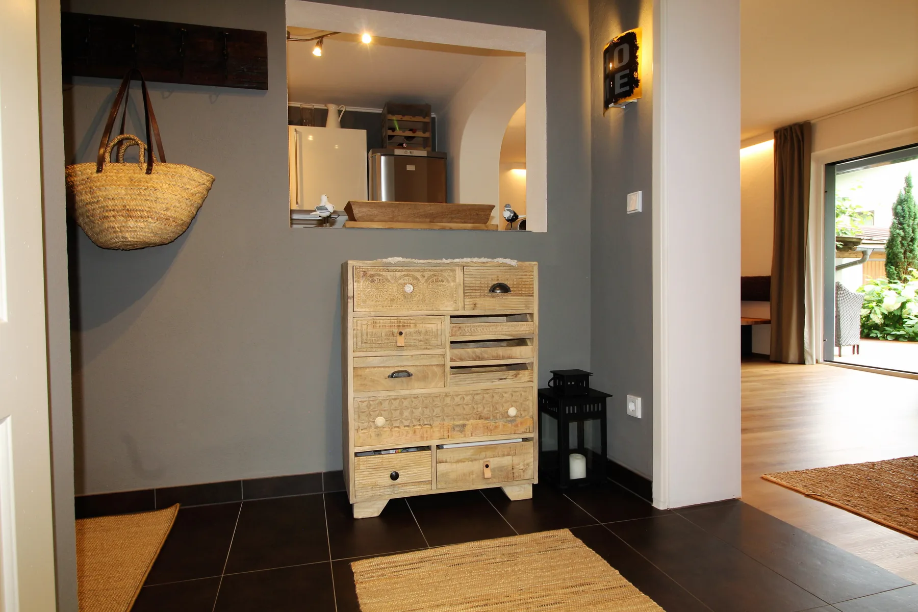 An entryway with a wooden chest of drawers and woven rugs.
