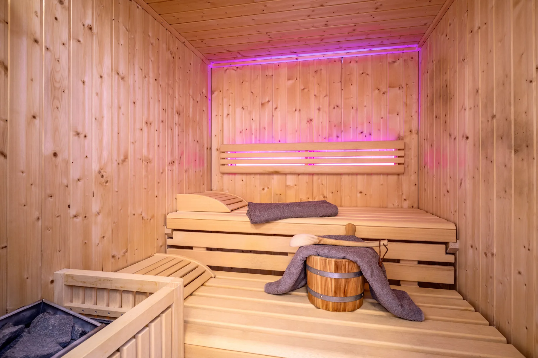 A wood-paneled sauna with tiered seating and colored lighting.