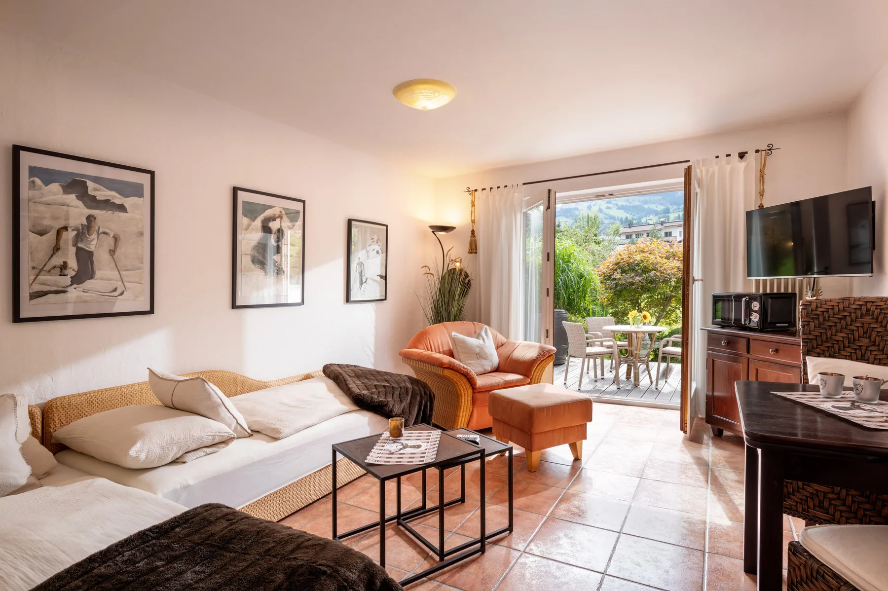 A bright studio living area with a bed, seating, and glass doors opening to a patio.