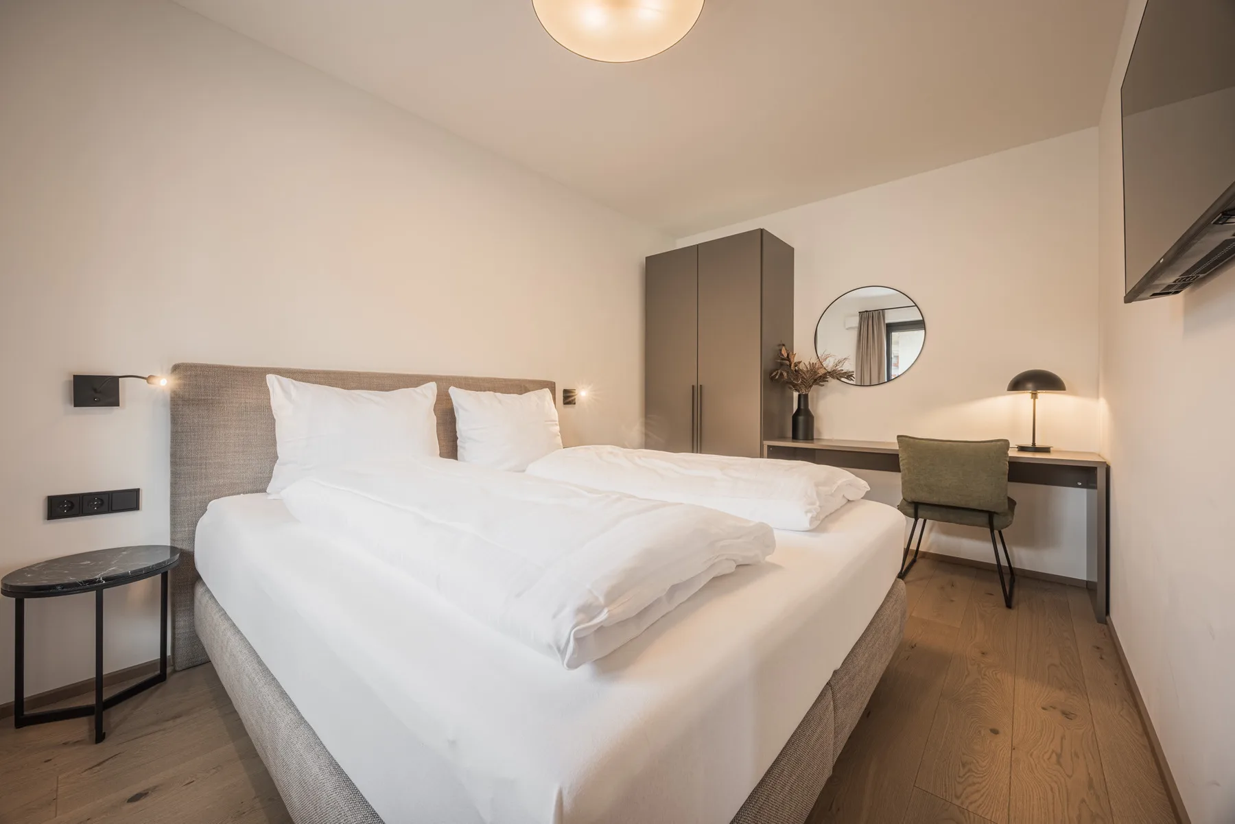 Un dormitorio con una cama bien hecha y un escritorio junto a la ventana.