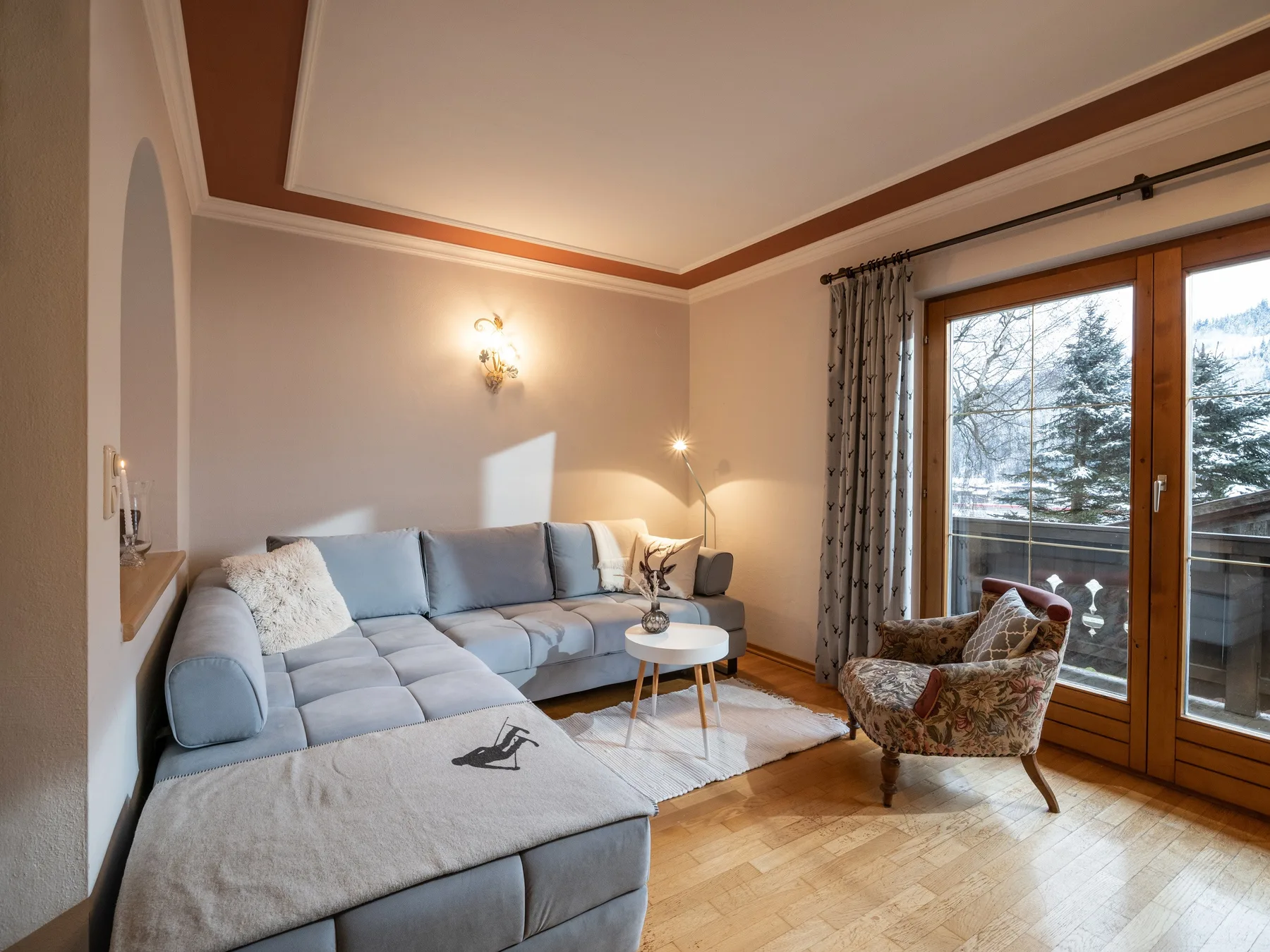 Una sala de estar con asientos, un sillón y puertas de vidrio que dan a un balcón.