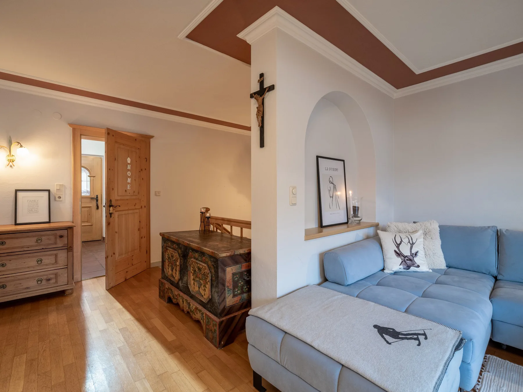 Una sala de estar con un sofá seccional azul junto a un mueble de madera.