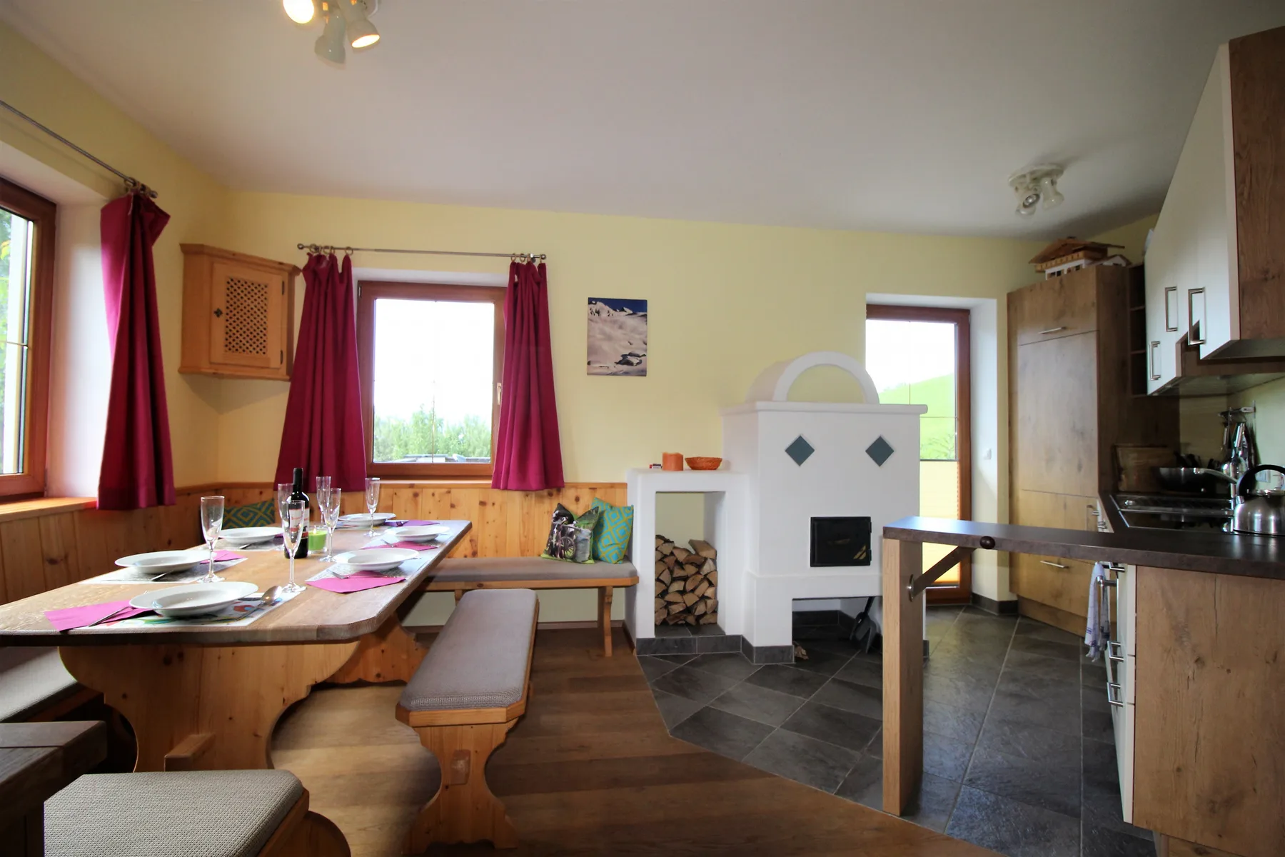 A dining area with a set table, wooden seating, and a white tiled stove.