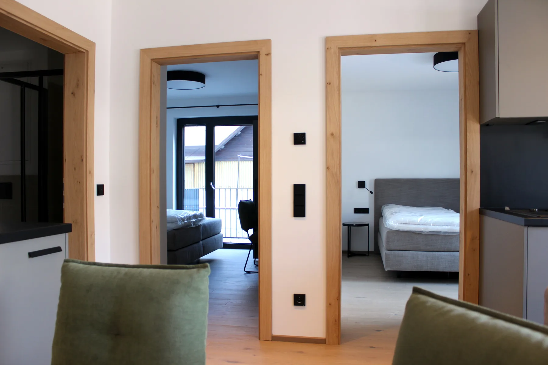 Interior view through wood-trimmed doorways into a living area and bedroom.