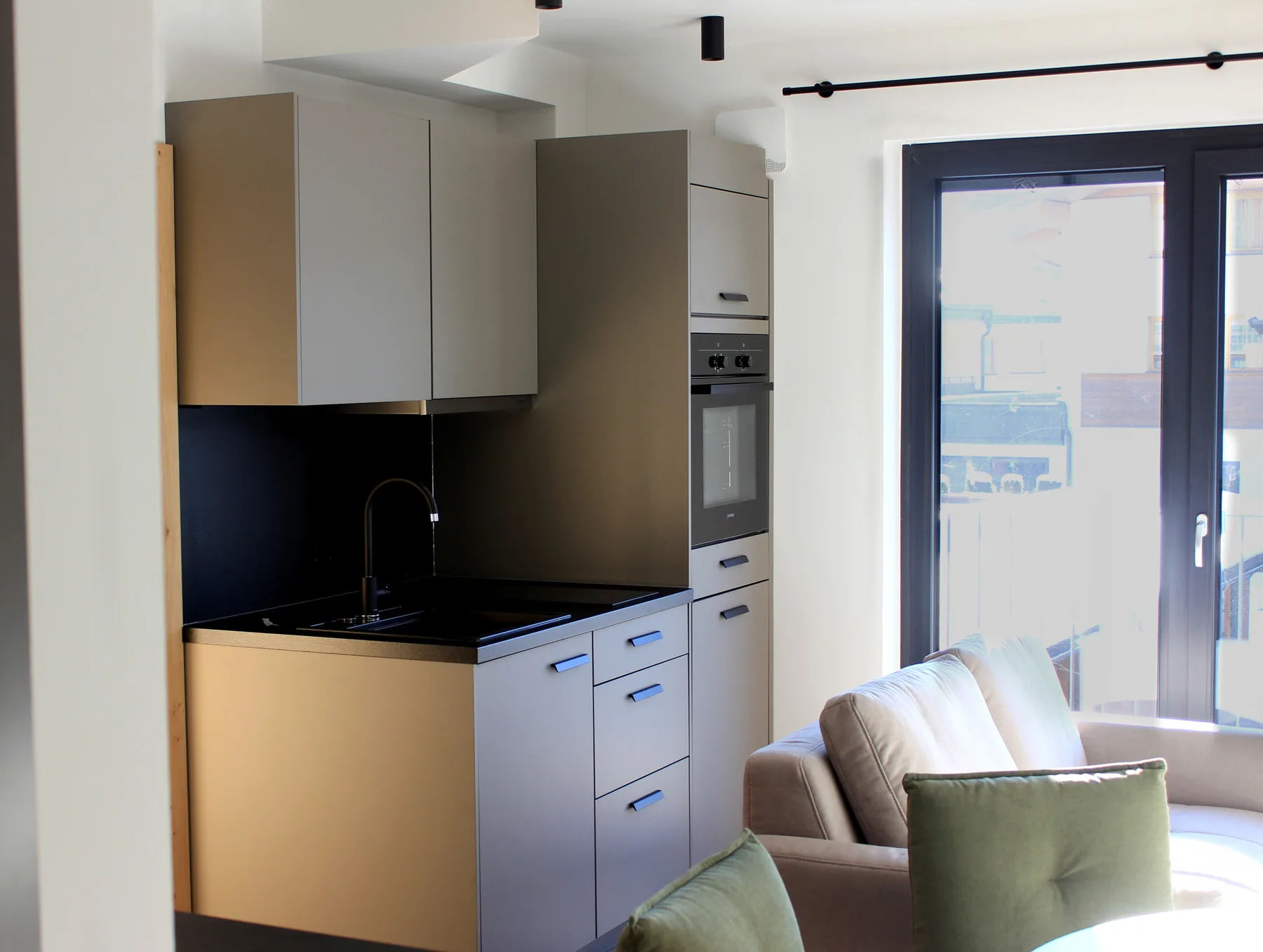 A modern kitchen opens onto a seating area beside a large glass door.