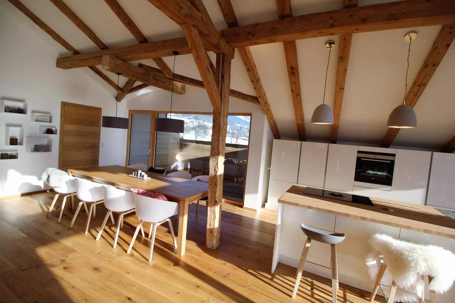 An open-plan dining area and kitchen beneath exposed wooden beams.