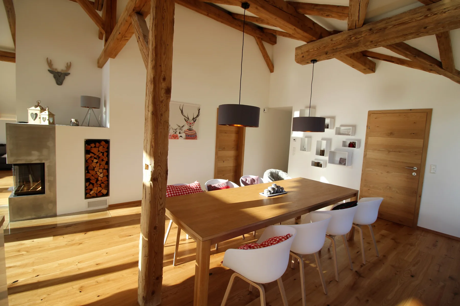A dining area with a wooden table, chairs, and exposed timber beams.