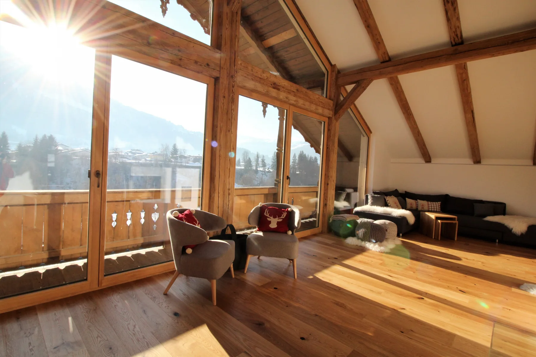 A bright living room with large windows and seating overlooking a mountain landscape.