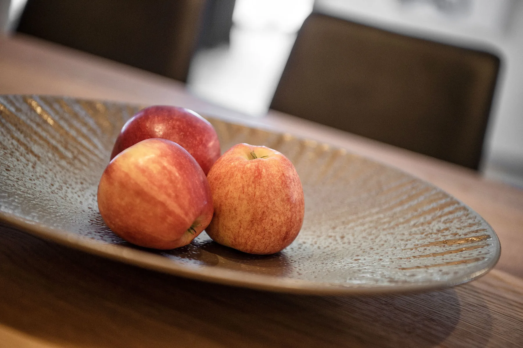 Una mesa de comedor sostiene un plato decorativo con varias manzanas.