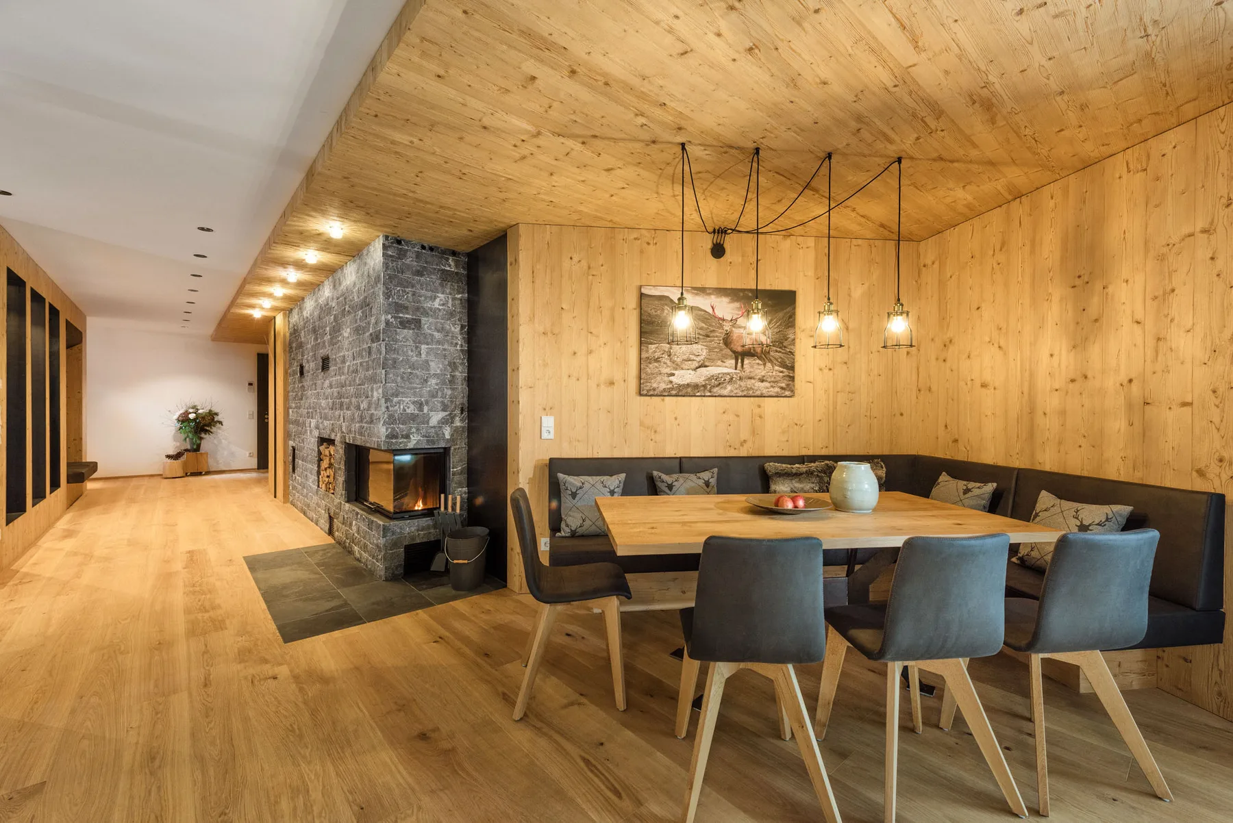 A dining area with a wooden table and seating beside a stone fireplace.