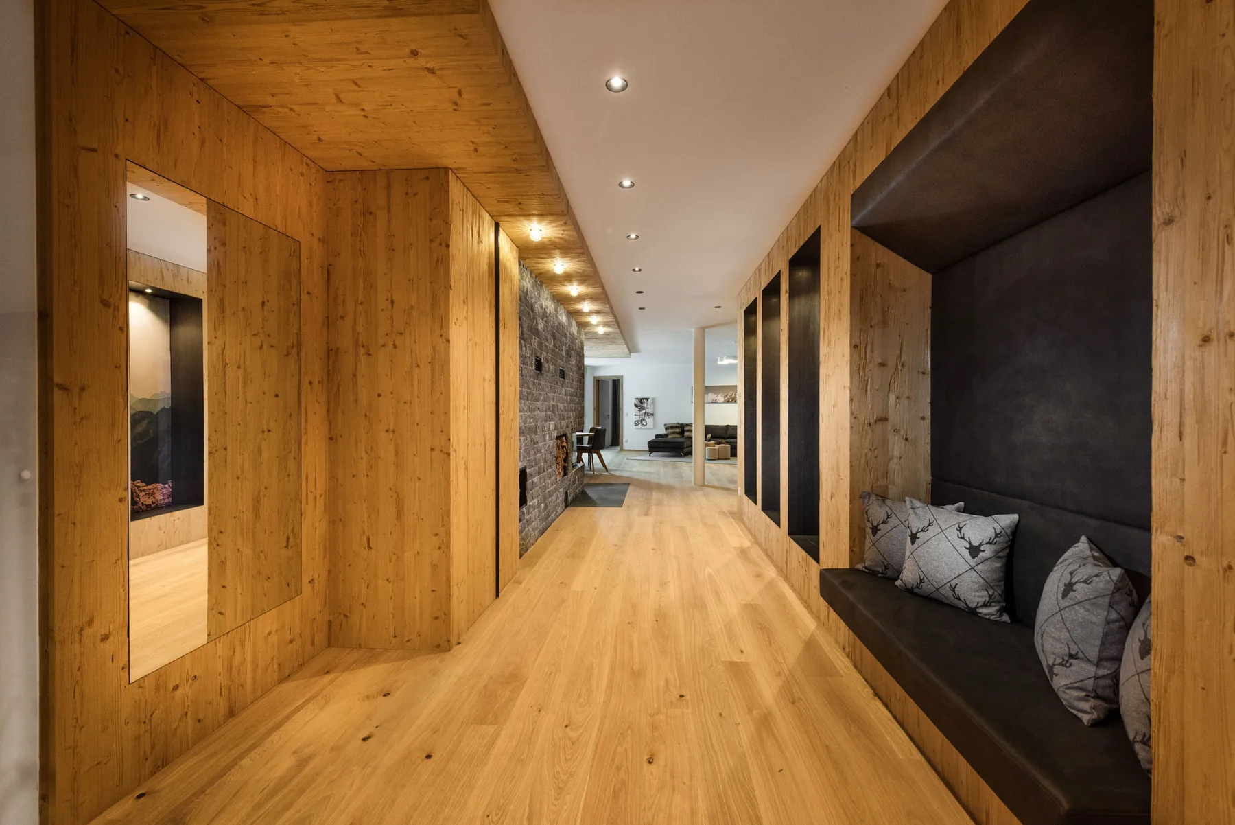 Un pasillo revestido de madera con un banco empotrado y una zona de estar al fondo.
