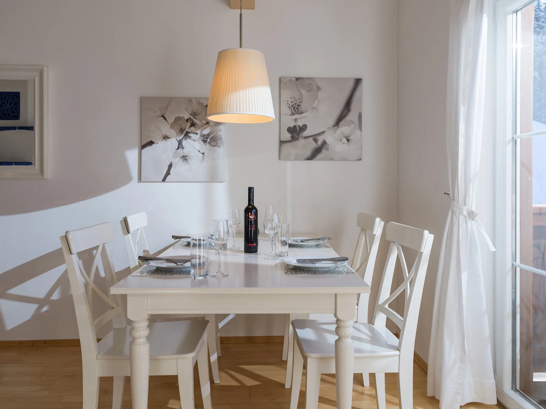 Un comedor con la mesa puesta junto a una ventana luminosa.