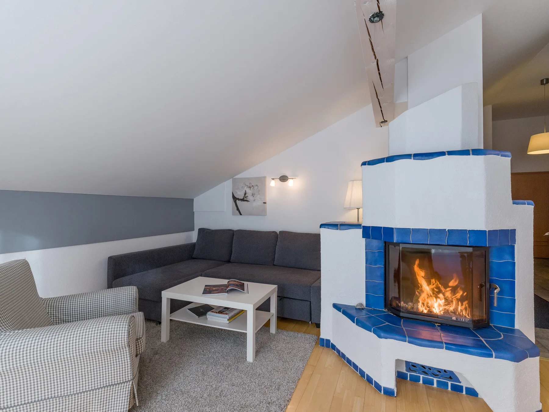 Una sala de estar con techo inclinado, asientos y una chimenea revestida de azulejos.