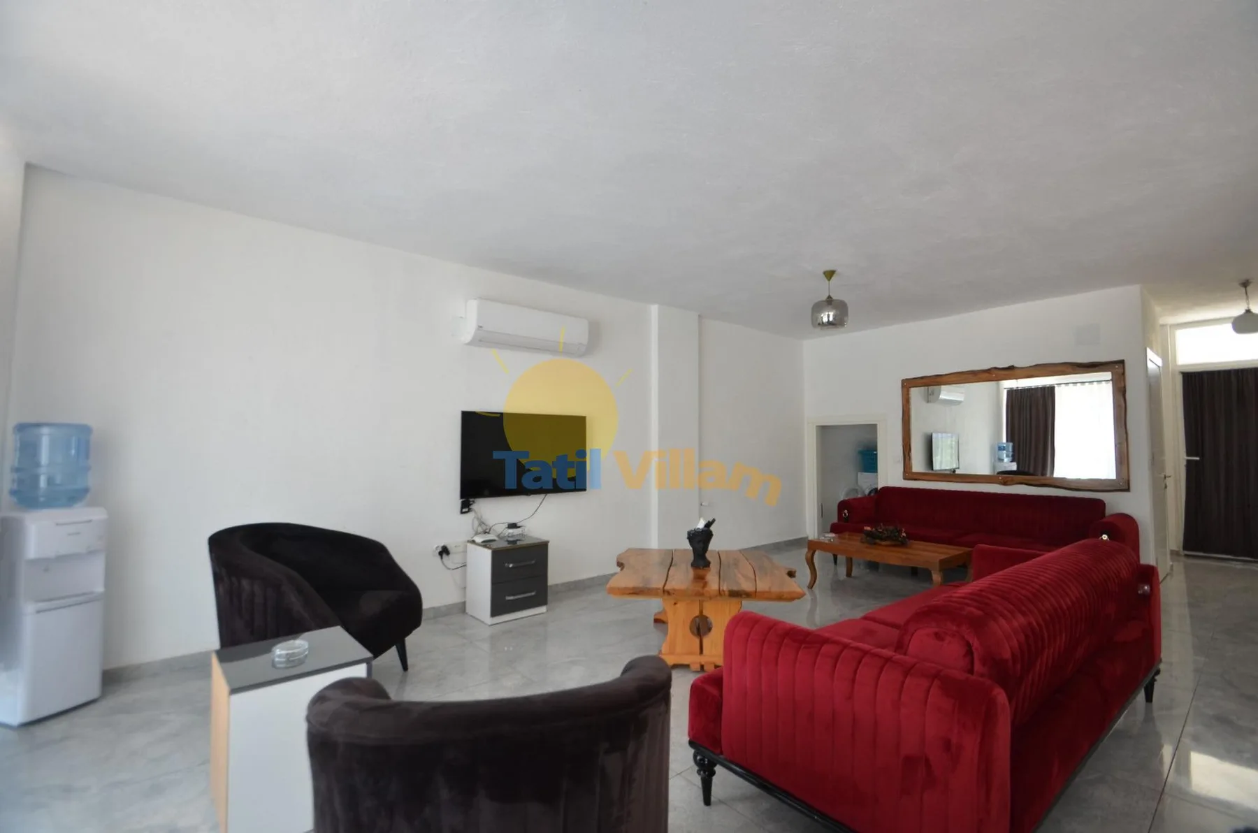 Una sala de estar con asientos rojos, sillones oscuros y un televisor.